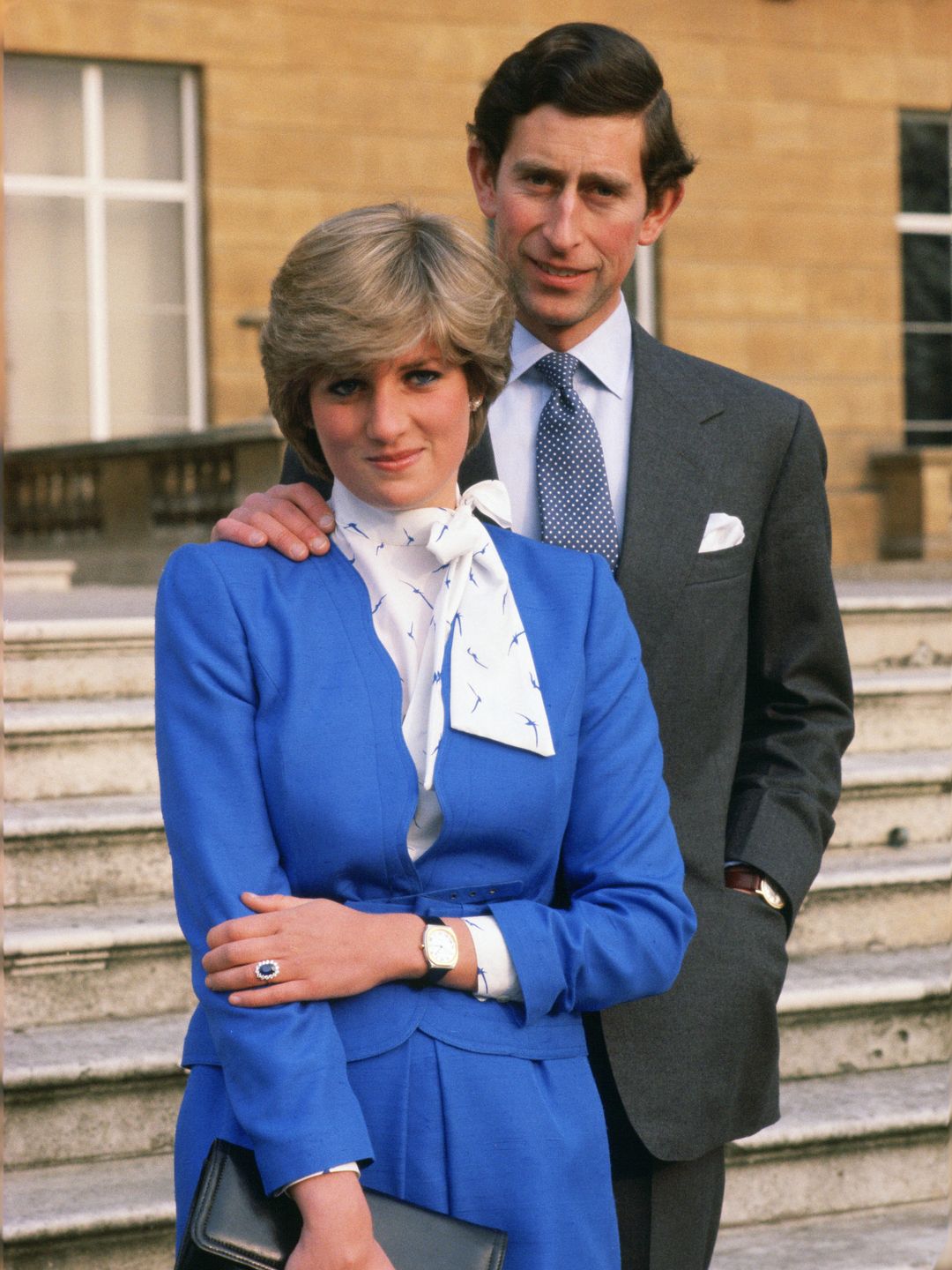 Princess Diana in blue with King Charles stood behind her