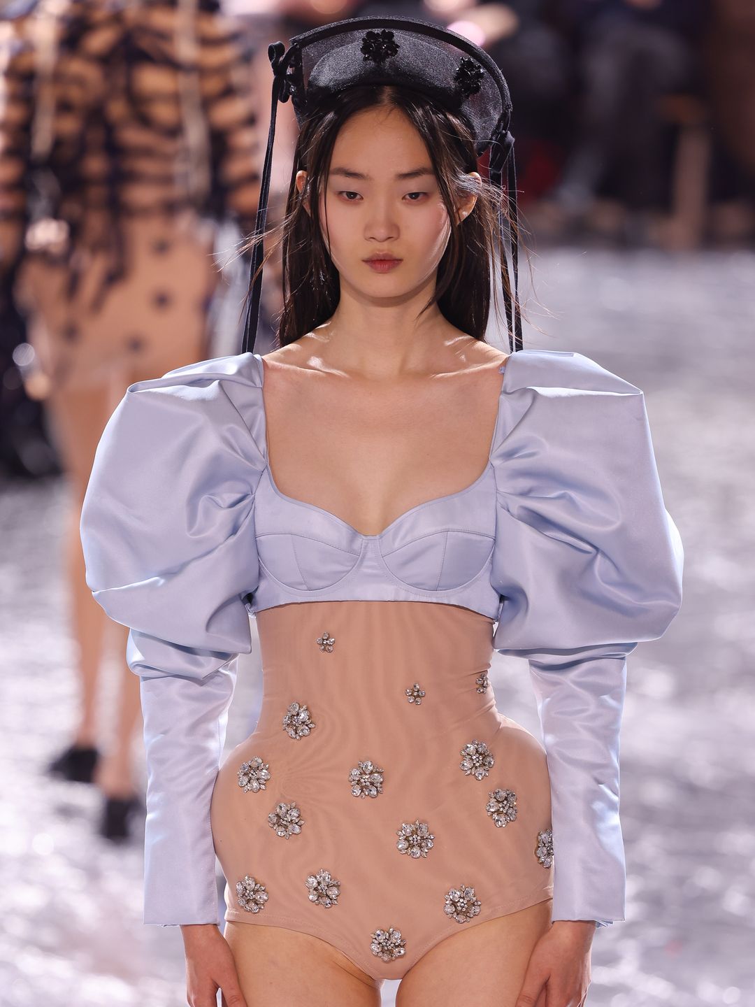 A model walks the runway during the Jean Paul Gaultier Haute Couture Spring/Summer 2024 wearing a baby blue puff sleeve shirt and crystal embellished bodysuit