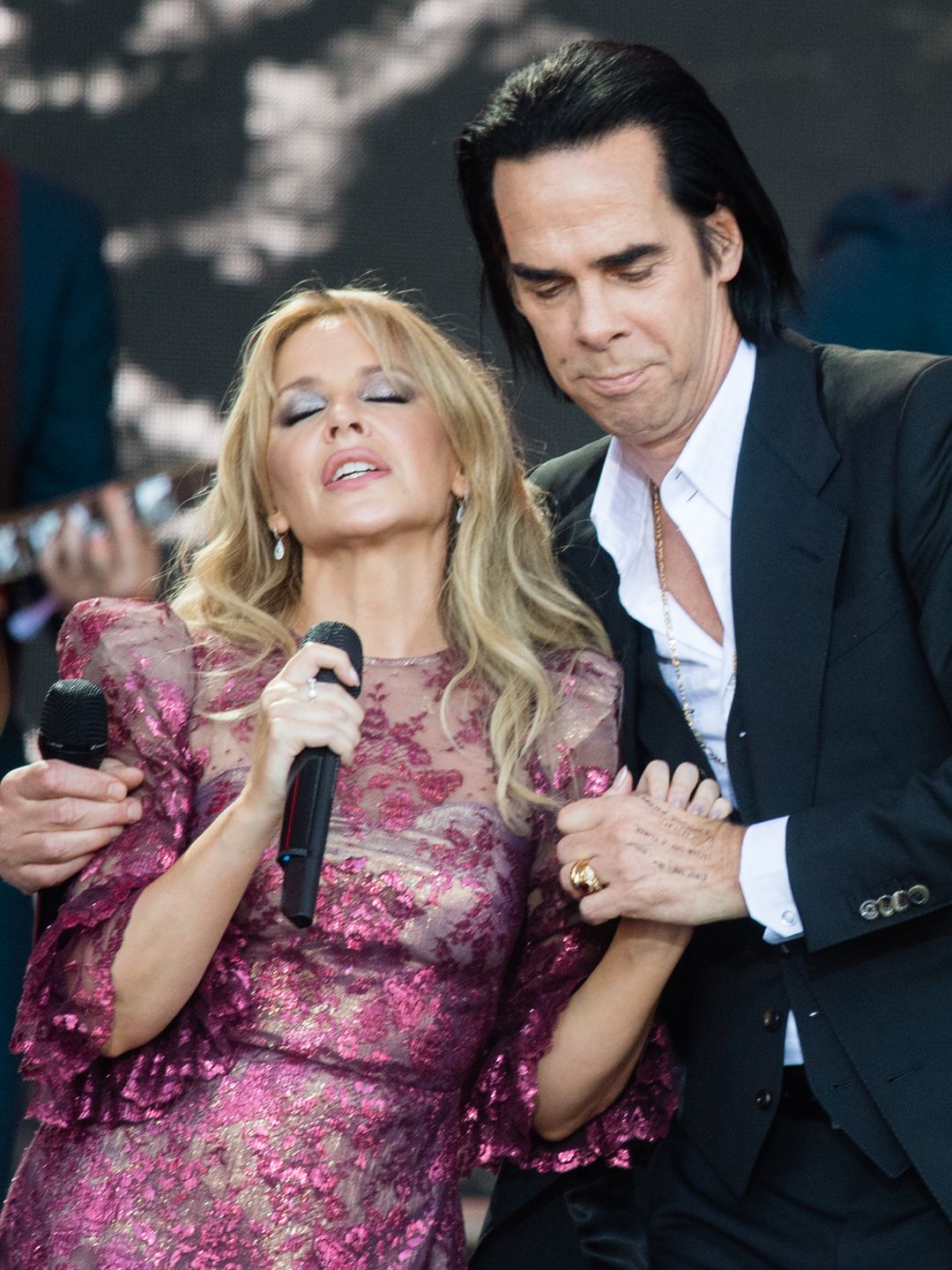Kylie Minogue wearing a pink puff-sleeve Vampire's Wife dress while performing onstage with Nick Cave 