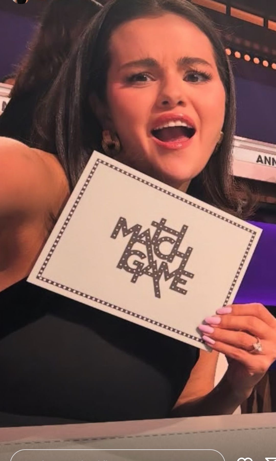 selena gomez holds up a white card 