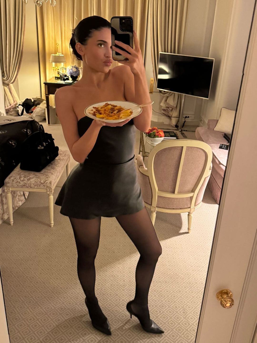 Kylie Jenner poses for a mirror selfie in a black mini dress and sheer tights