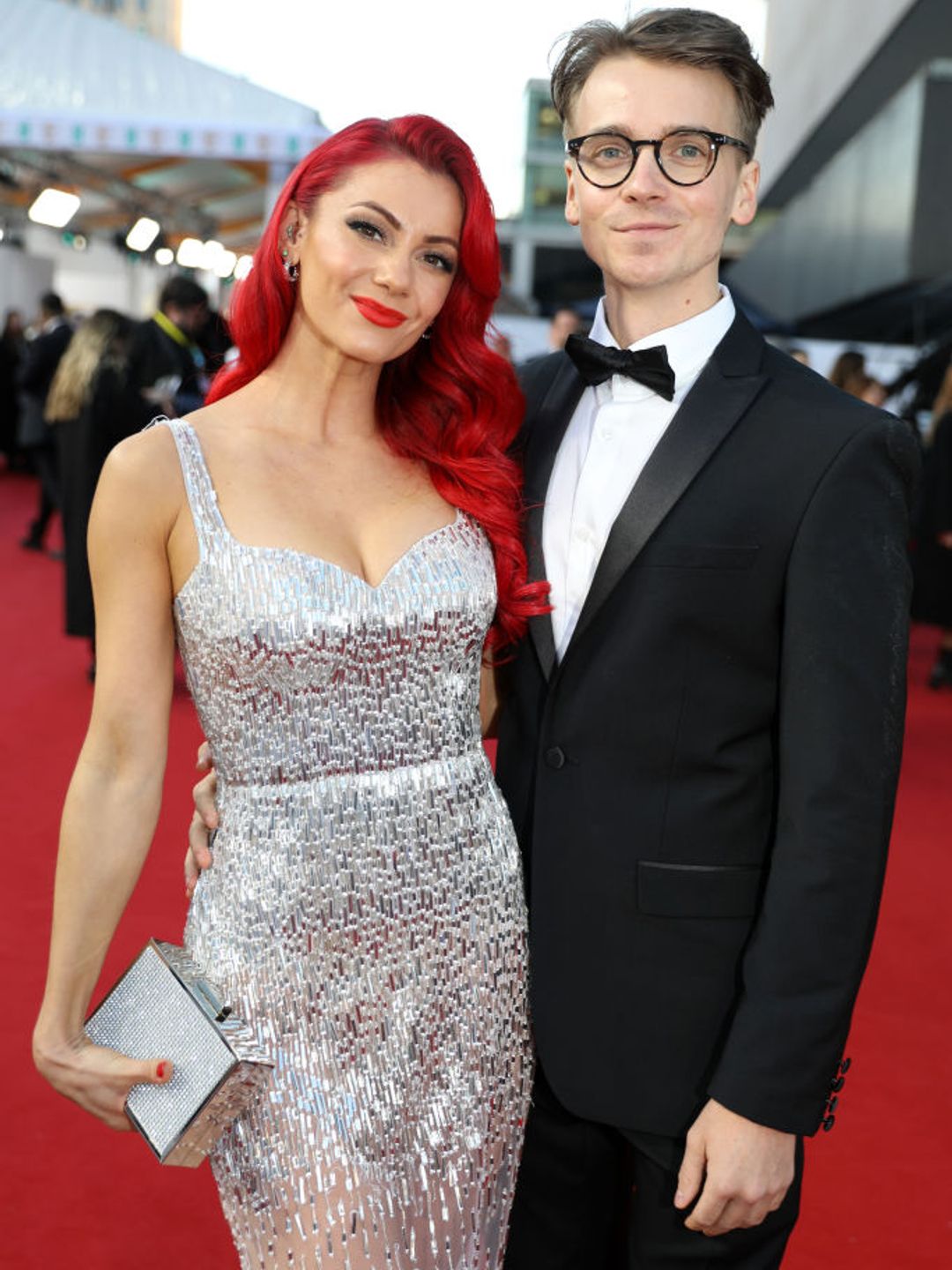 Dianne Buswell wearing a silver beaded gown and Joe Sugg in a black tux as they attend the EE BAFTA Film Awards 2023