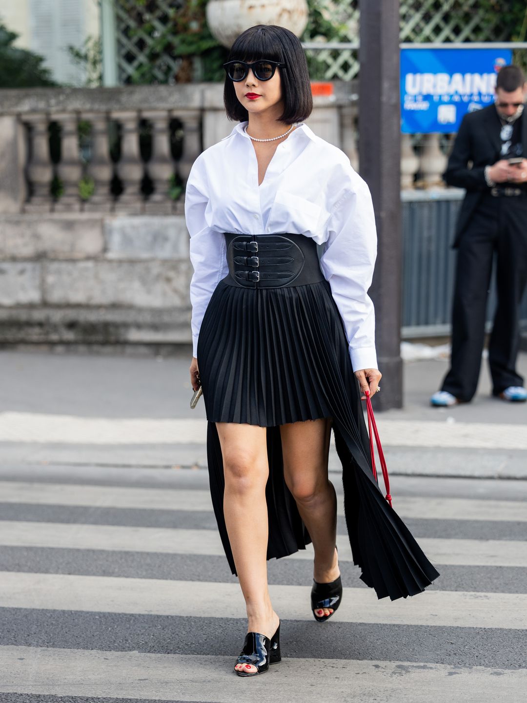 A guest championed the pleated skirt, styling a black mini with a multi-buckle corset belt and glossy mules.