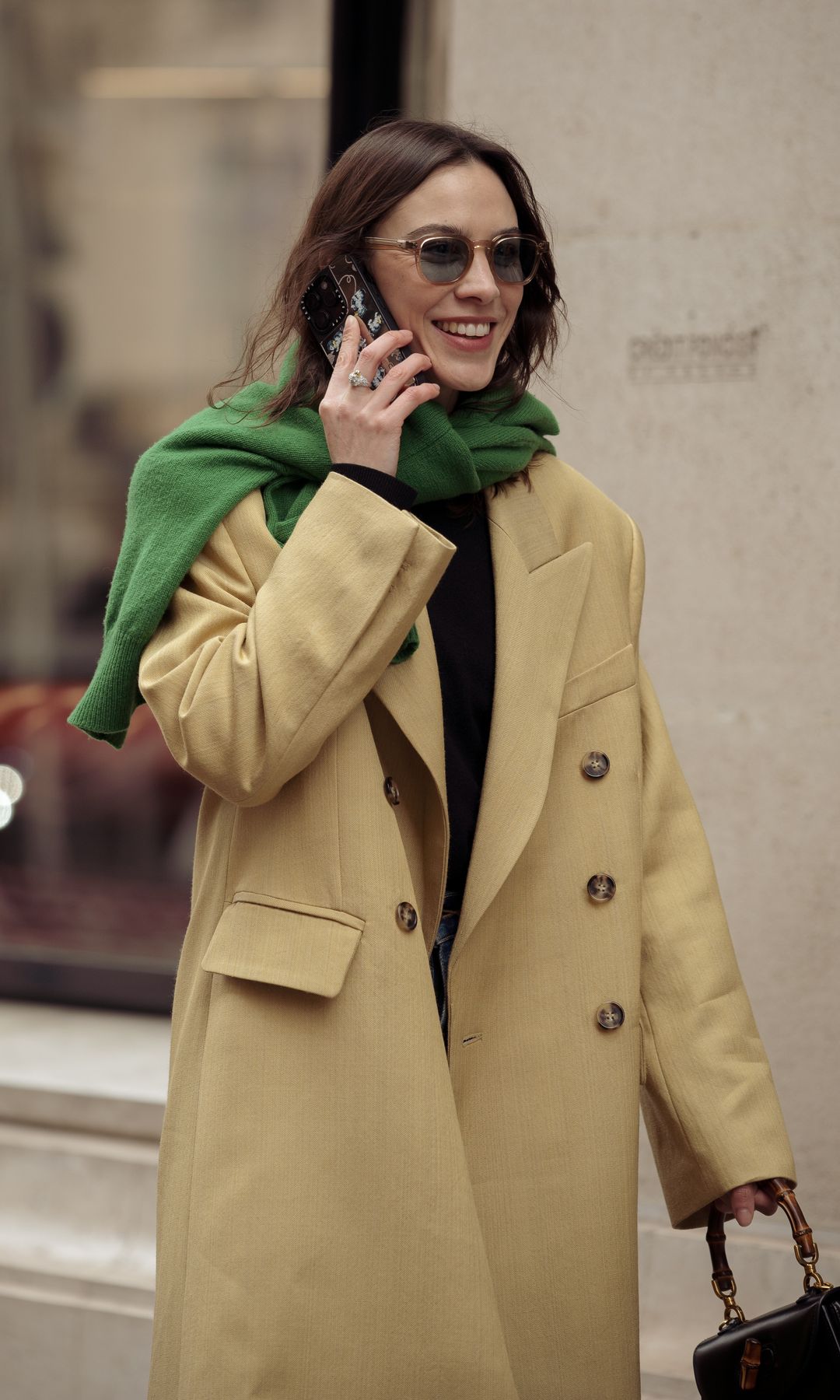  Alexa Chung wears blue jeans, beige coat and green sweater over the shoulders outside The Row during the Womenswear Fall/Winter 2024/2025 as part of  Paris Fashion Week on February 28, 2024 in Paris, France.