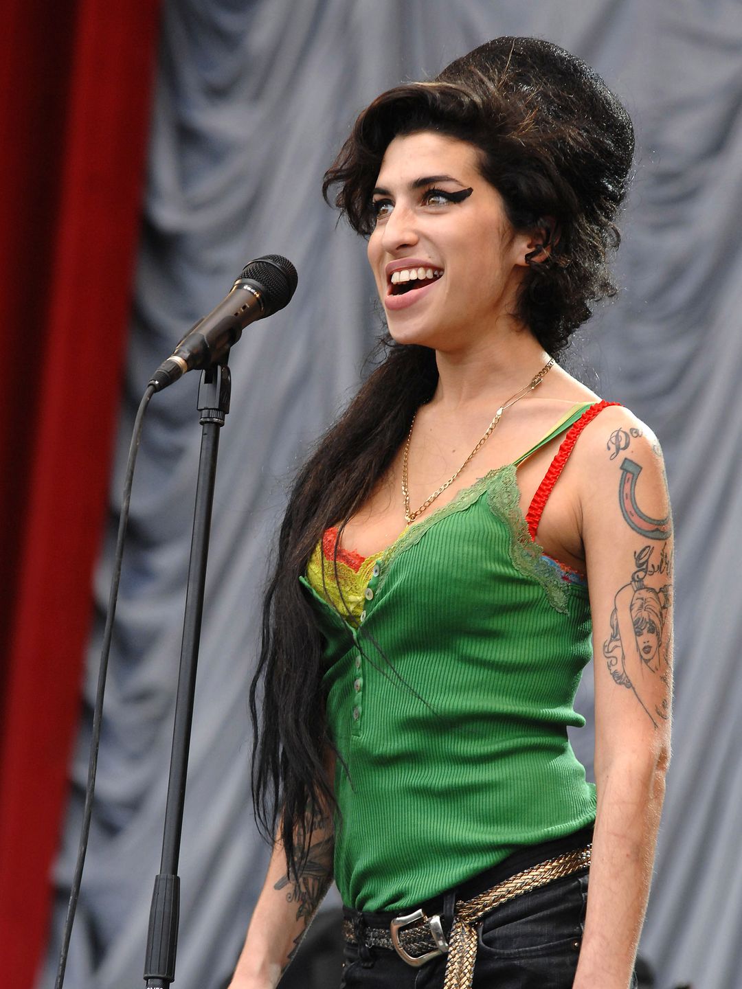 Amy Winehouse in a green lace cami top with thick black eyeliner 