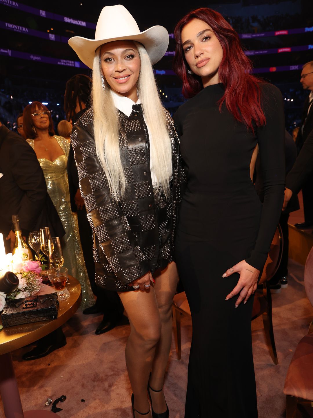 Dua Lipa poses with Beyonce at the 66th GRAMMY Awards. Dua wears a black gown while Beyonce wears a Louis Vuitton blazer dress and cowboy hat