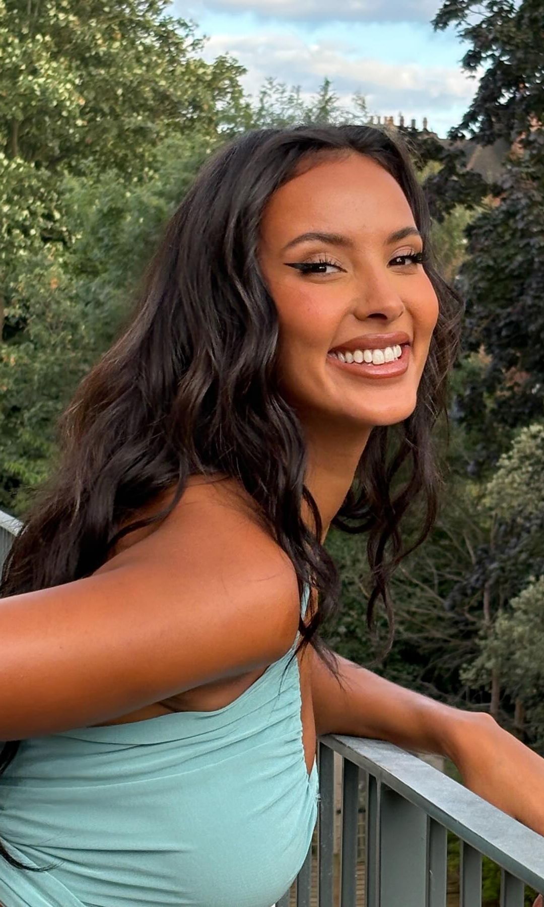 Maya Jama poses for a picture smiling in a blue crop top