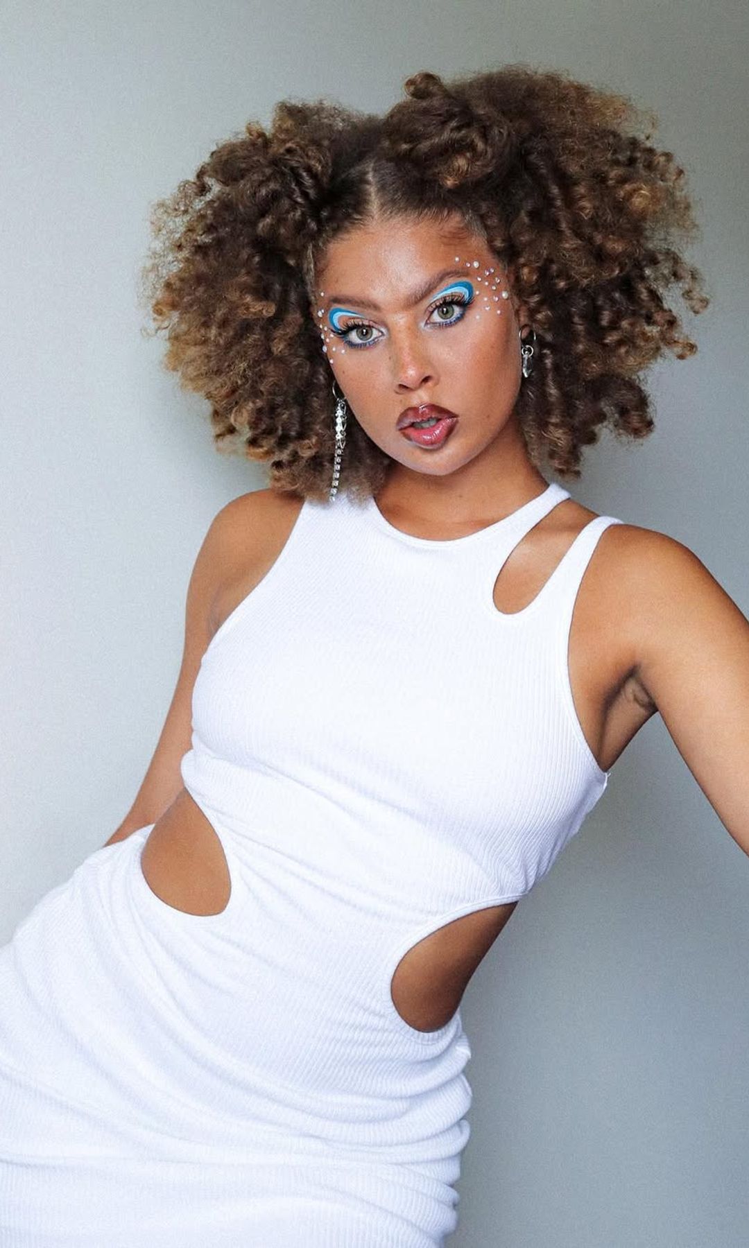 a girl with light brown curly hair and space buns 