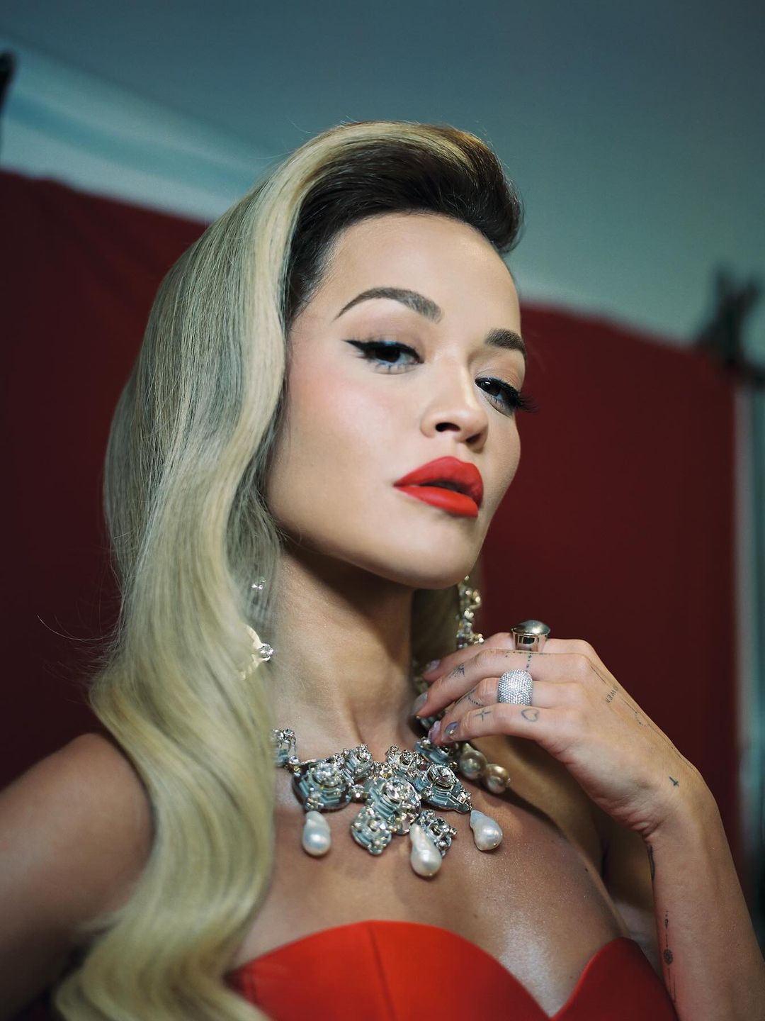 Rita Ora poses in a red lip look, a red mini dress and chunky necklace on her Instagram