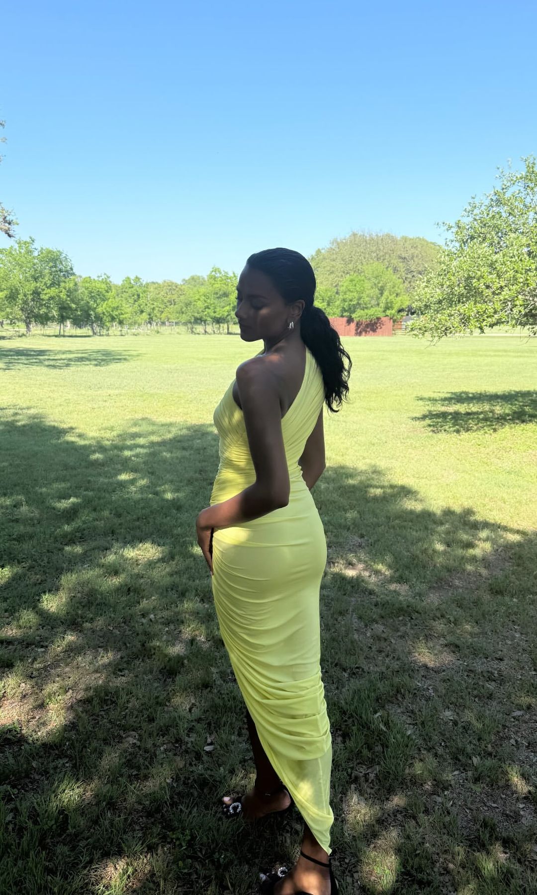 Simone Ashley wears a yellow dress to walk through a grassy field 