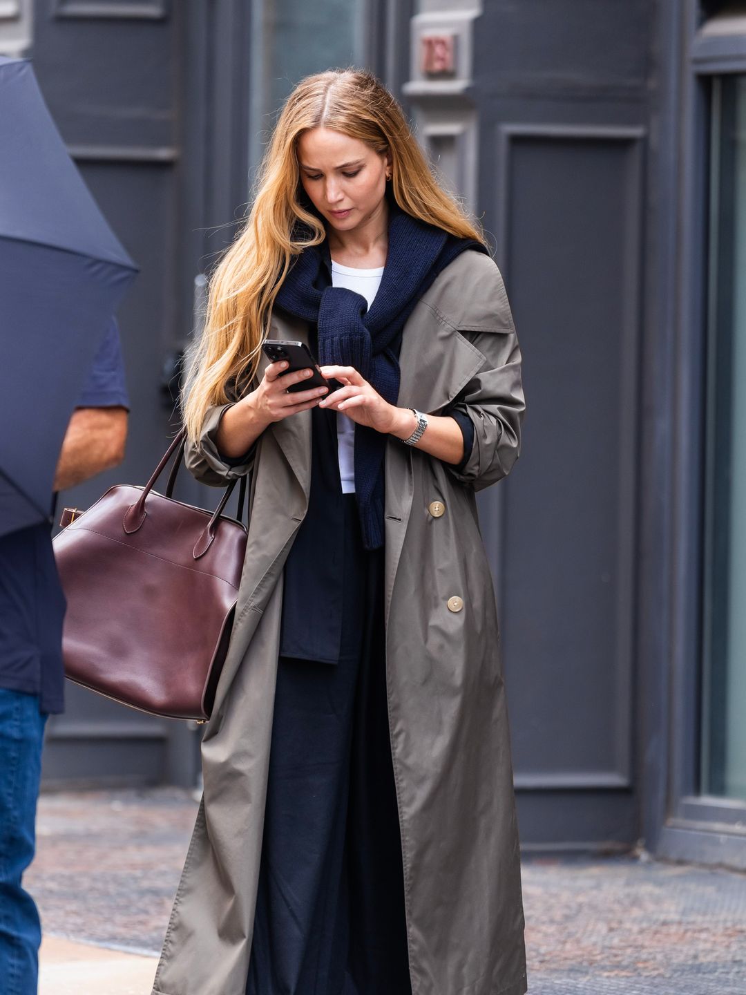 Jennifer Lawrence is seen in SoHo on June 28, 2023 wearing a long green trench coat over a navy blue suit