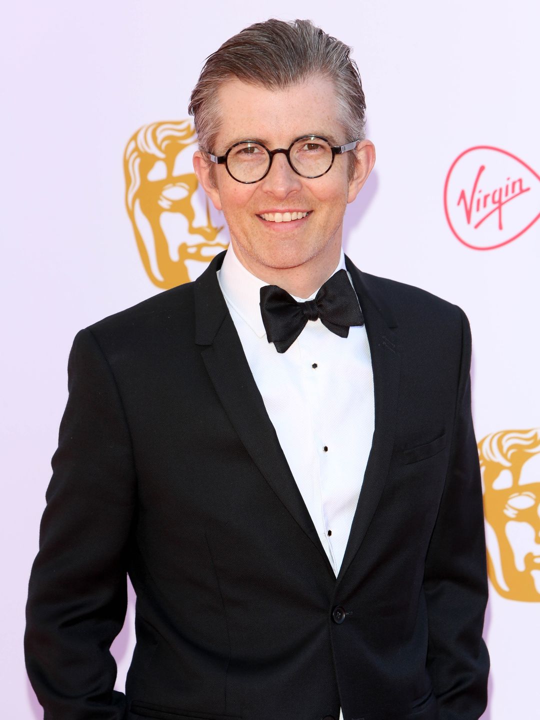Gareth Malone stands in a suit on red carpet at the BAFTAs
