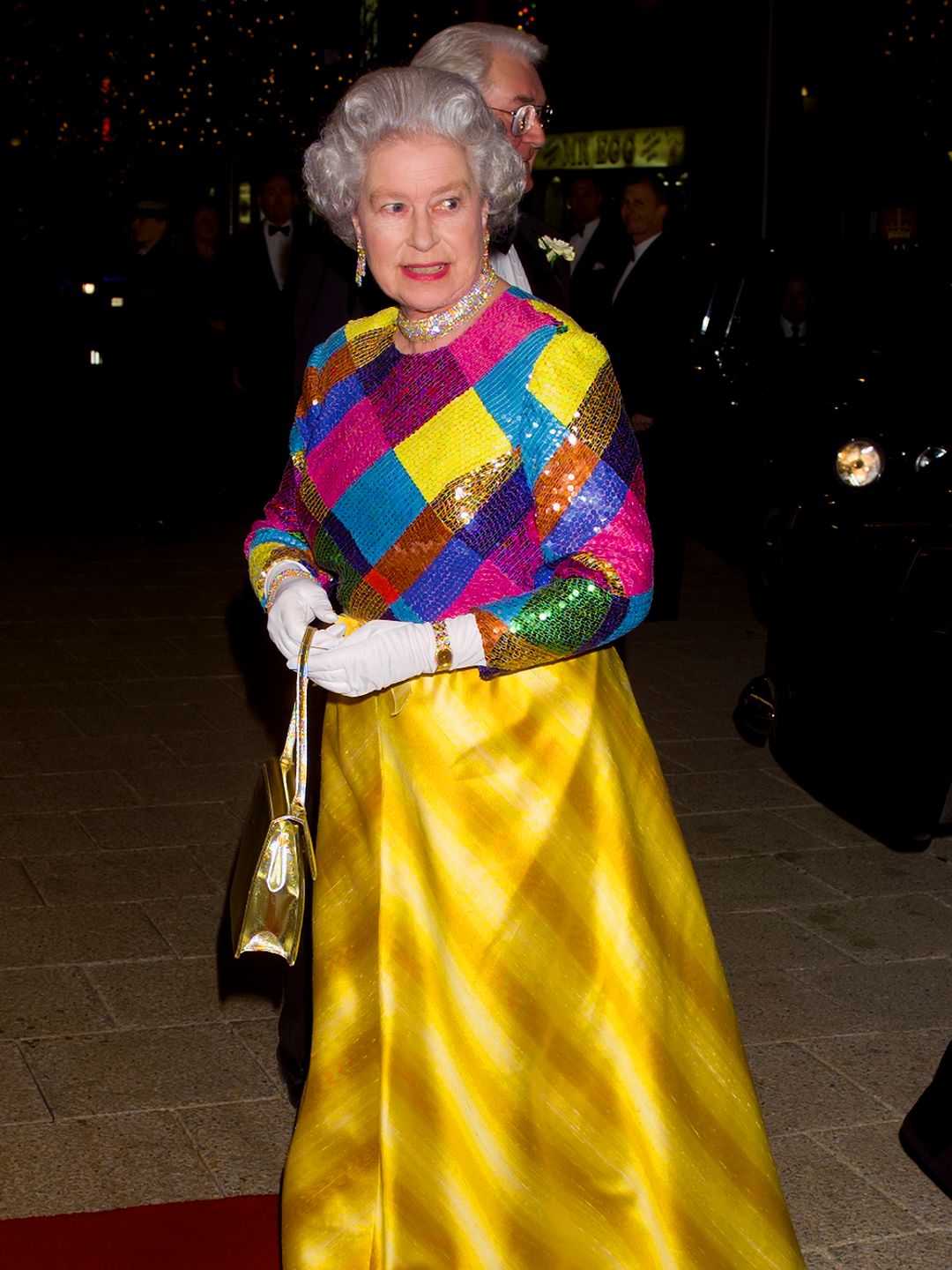 queen wearing bright dress on red carpet