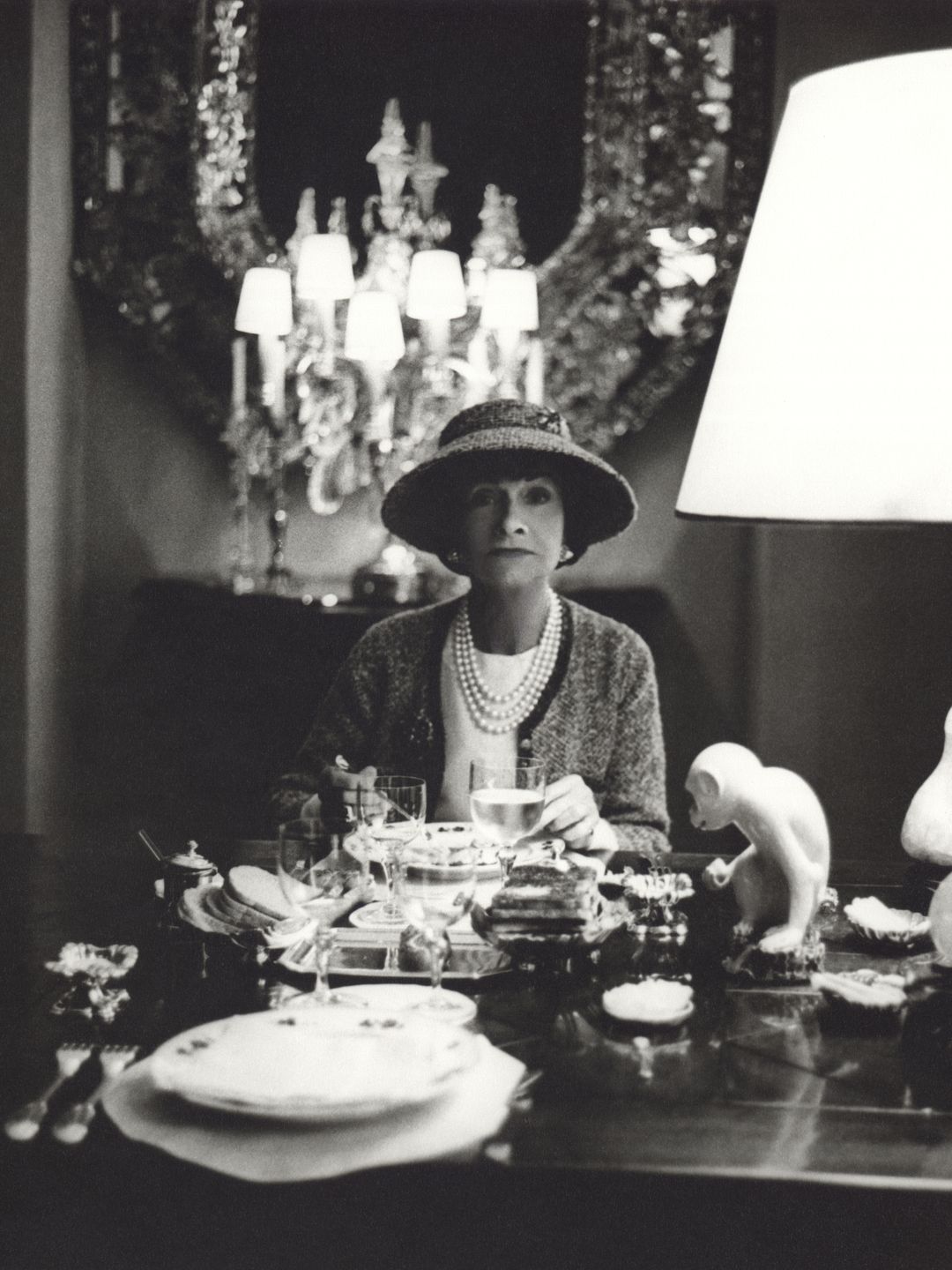 Fashion designer Coco Chanel, c. 1963, in her Paris apartment wearing a classic Chanel hat.