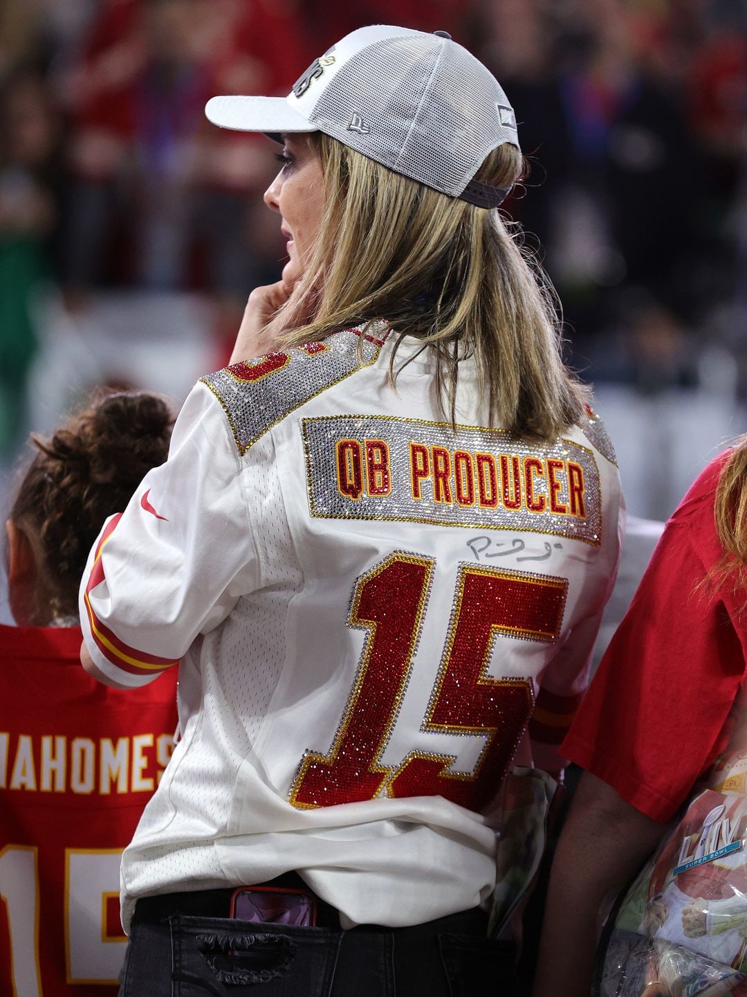 Randi Martin watching a Kansas City Chiefs game in 2020, her back is to the camera and her shirt says QB Producer