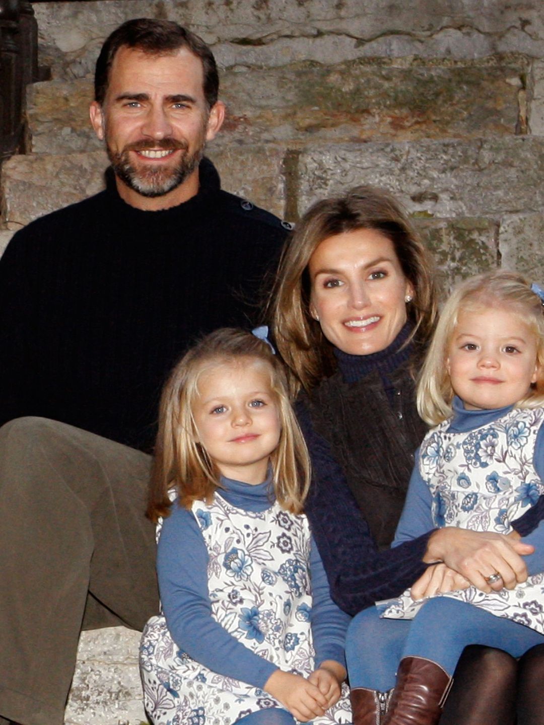 King Felipe in a black turtleneck with Queen Letizia holding a young Princess Leonor and Infanta Sofia