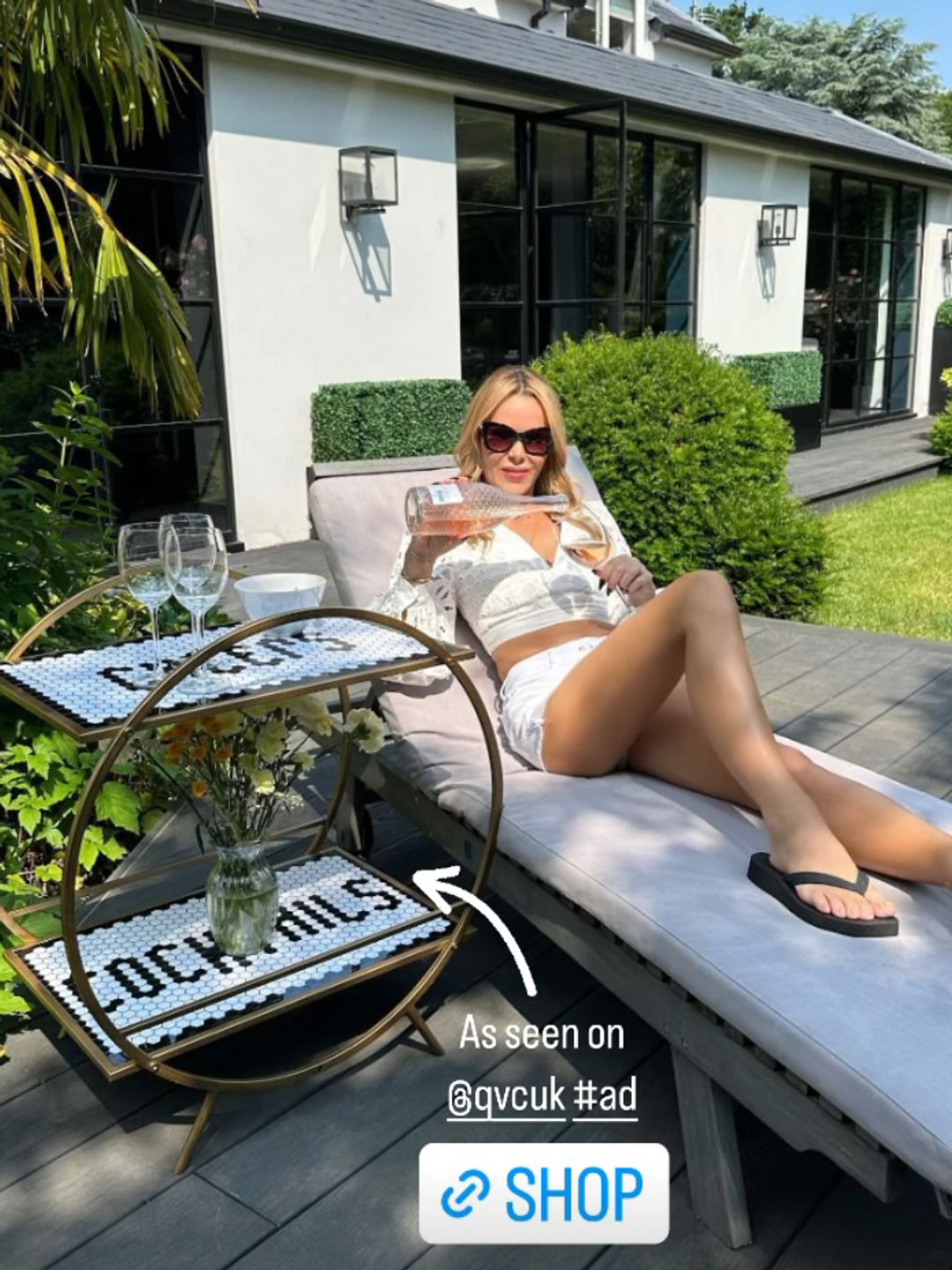 Amanda Holden wearing white shorts and a crop top as she sunbathes in her garden