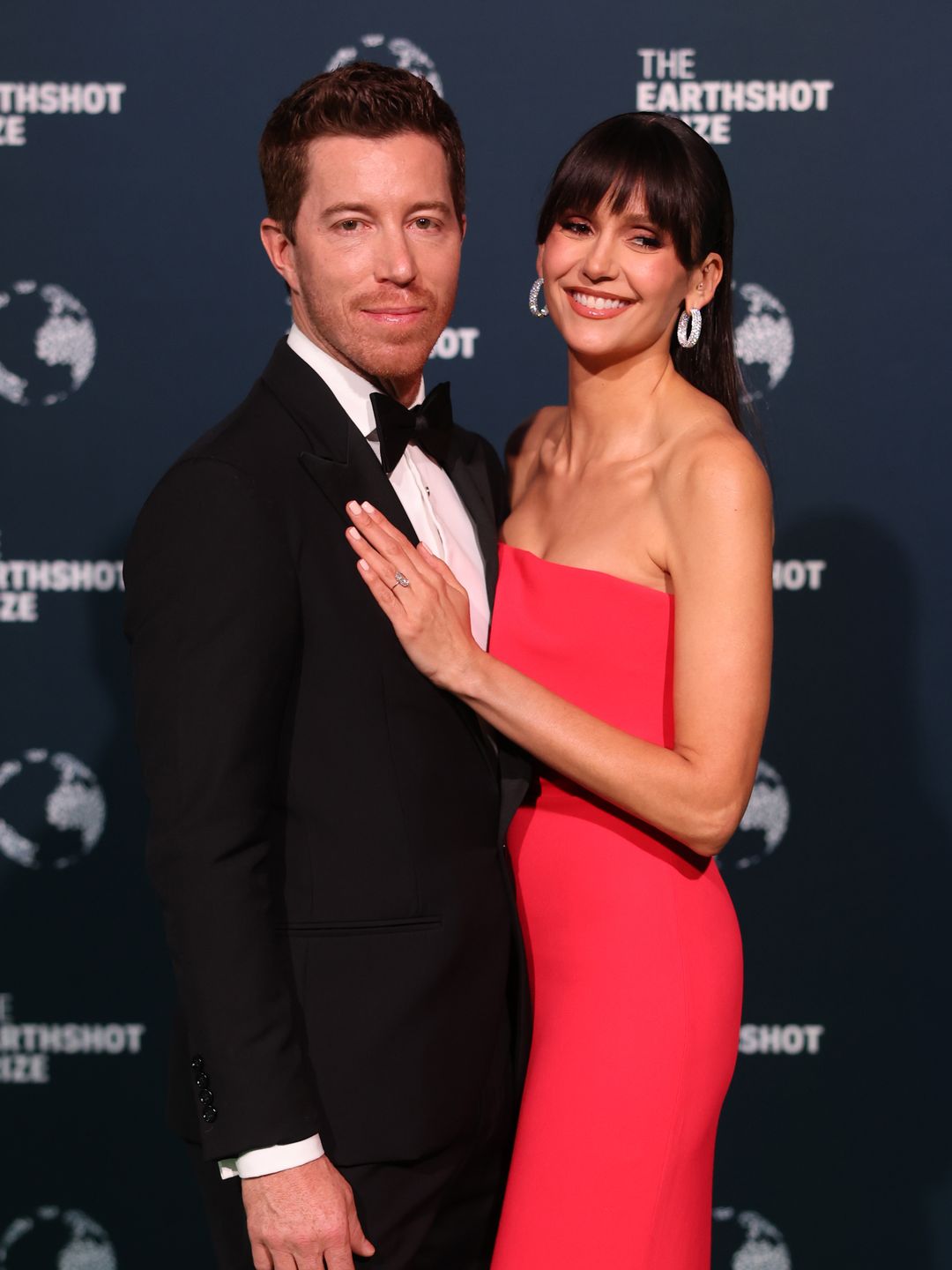 Shaun White in a black tuxedo and Nina Dobrev in a red dress