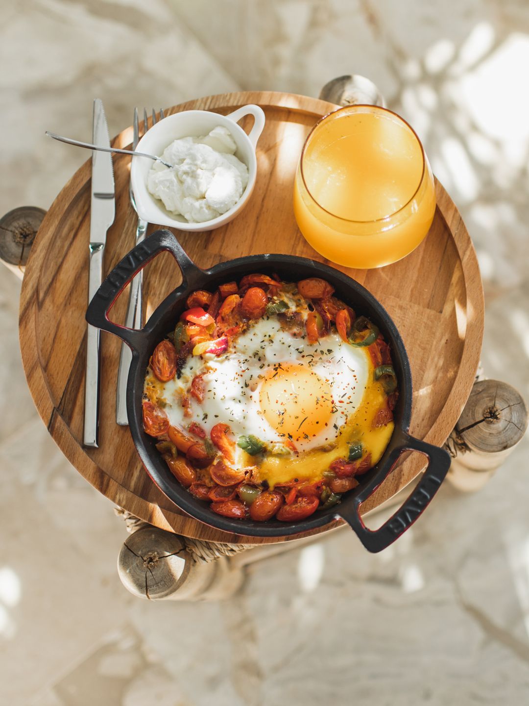 Tray with tasty breakfast on bed in light room.