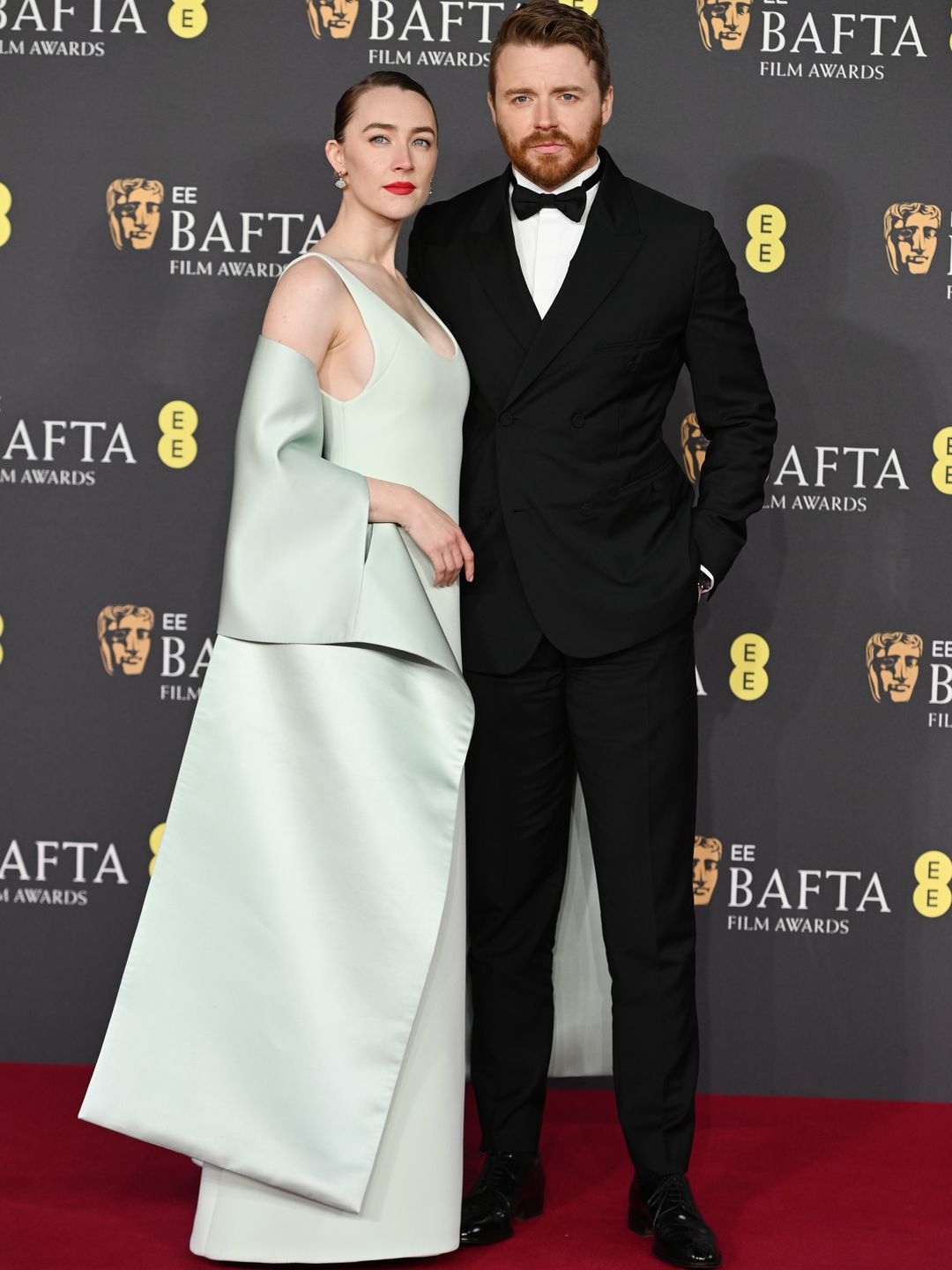 Saoirse Ronan in a white dress on the red carpet with Jack Lowden