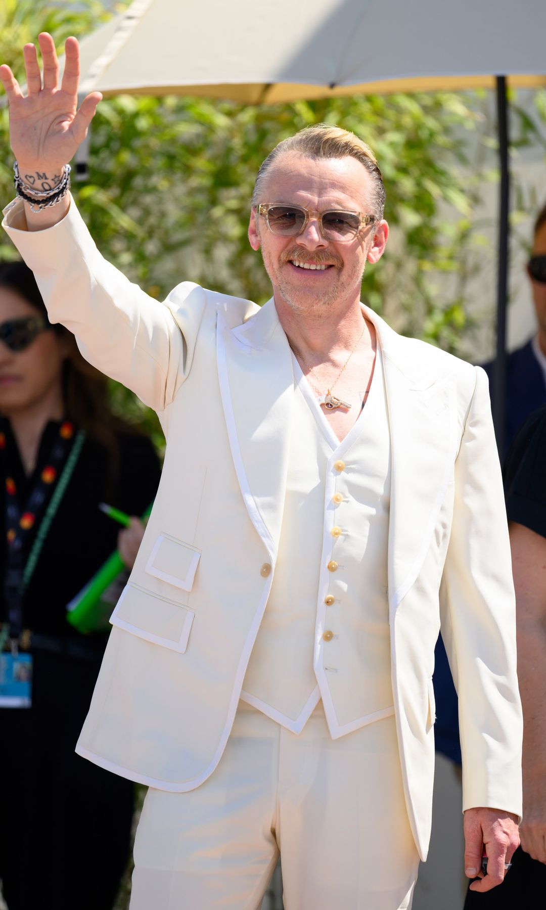 Simon Pegg waving in a white suit