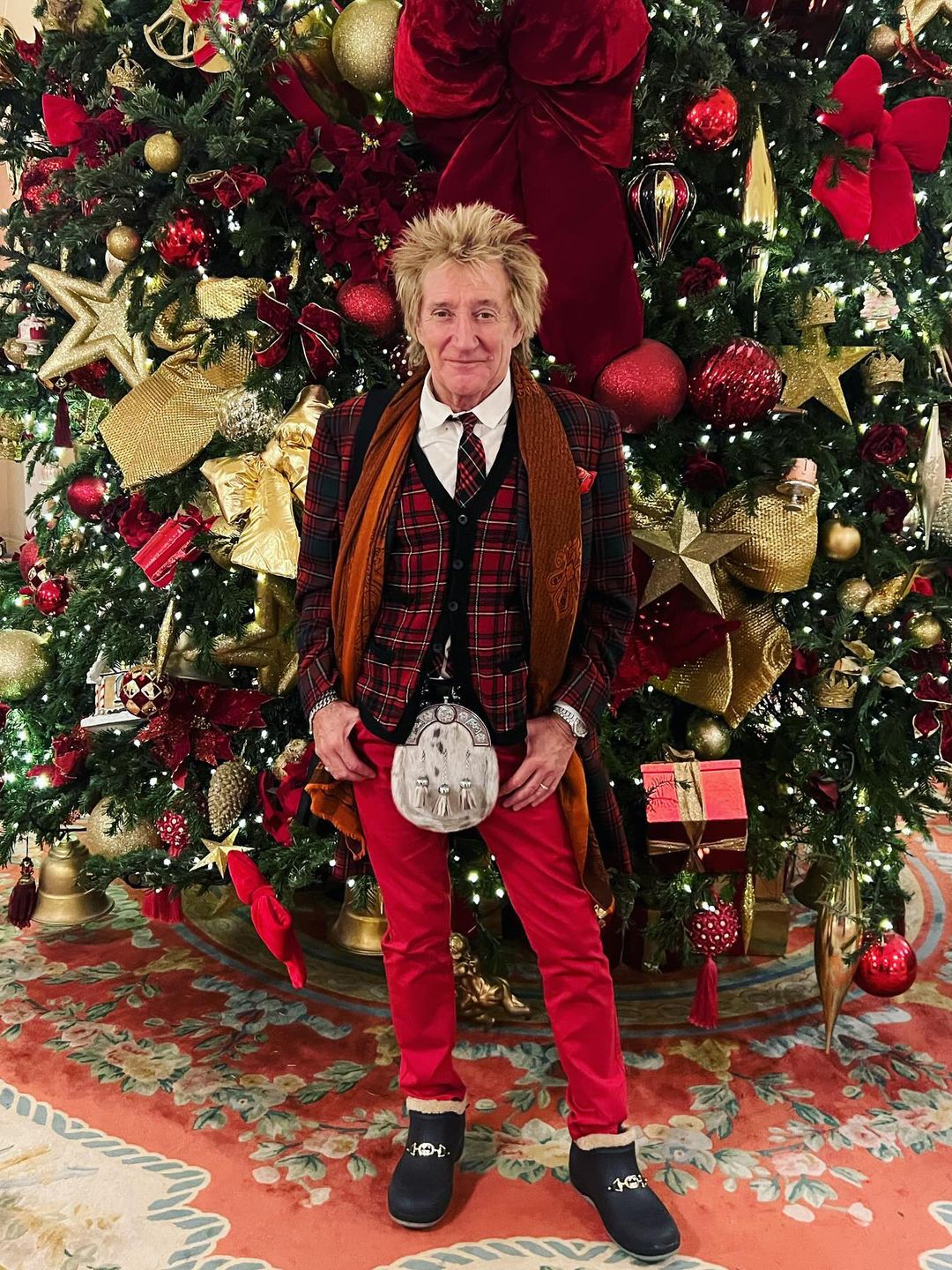Rod Stewart standing by a huge Christmas tree
