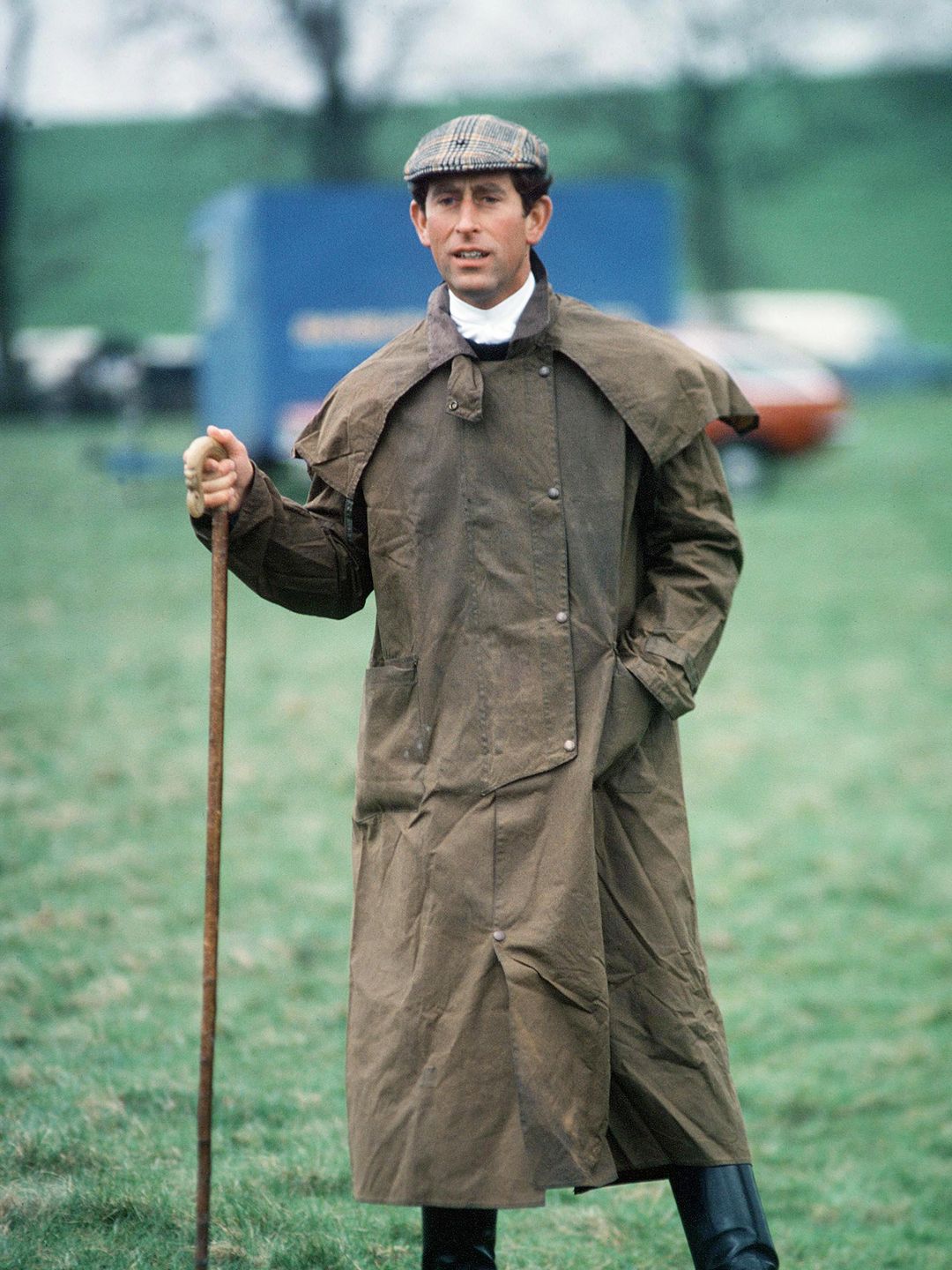 man in long wax coat with walking stick 