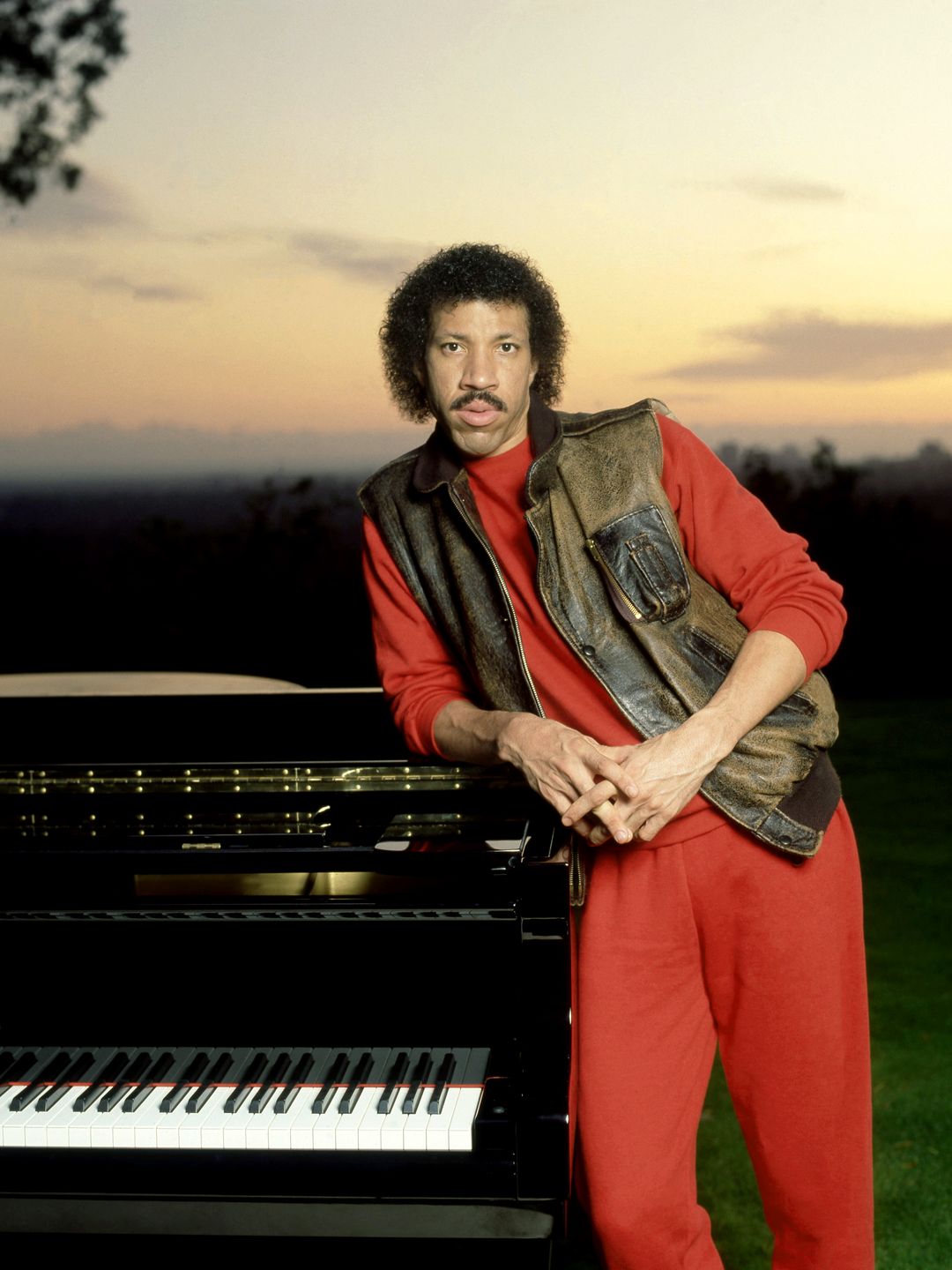 American singer Lionel Richie poses for a portrait with his piano and sunset in Los Angeles, California, circa 1983. 