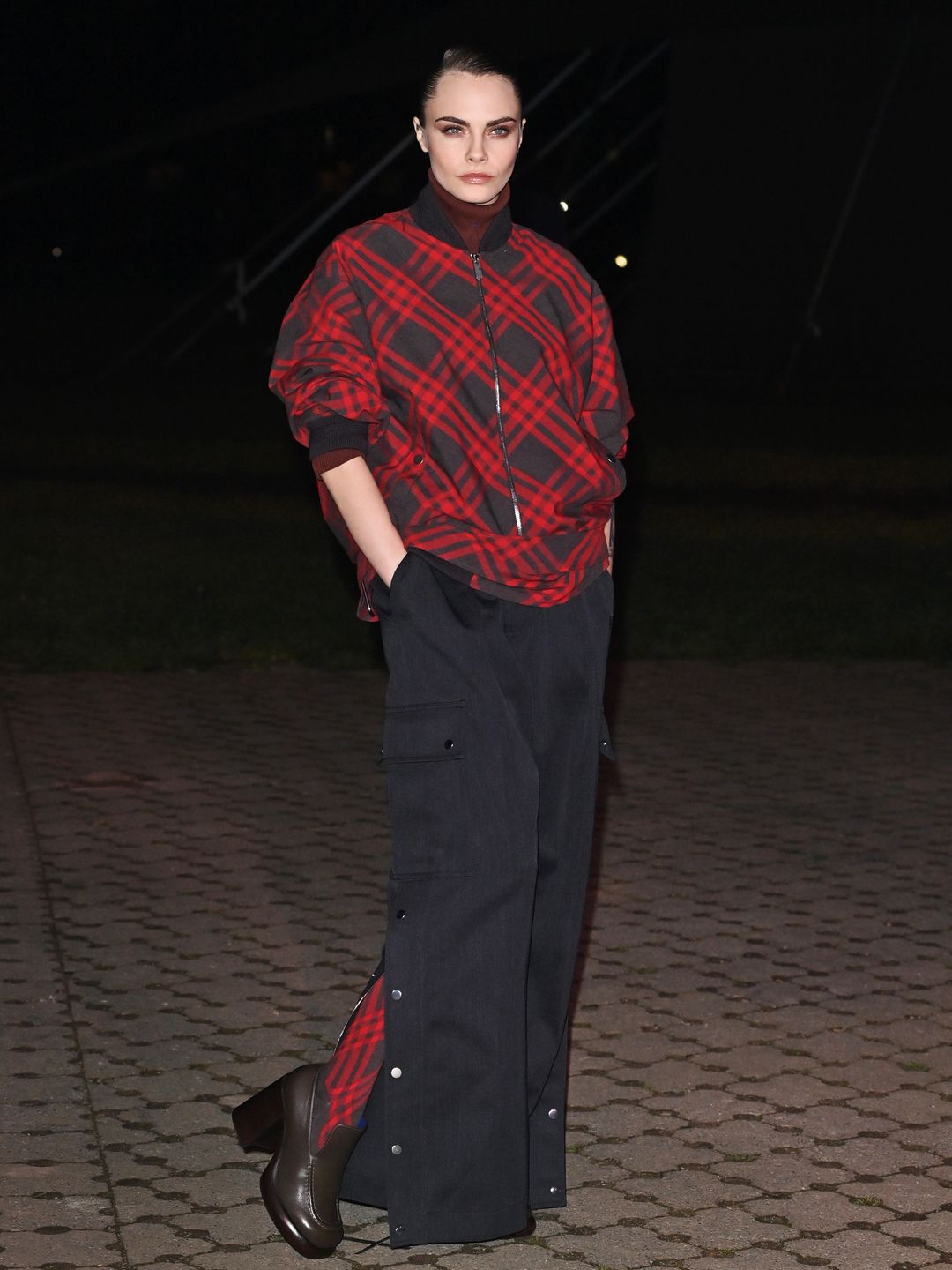 Cara Delevingne chose a red and black checkered bomber jacket and matching tights ensemble for the Burberry show.