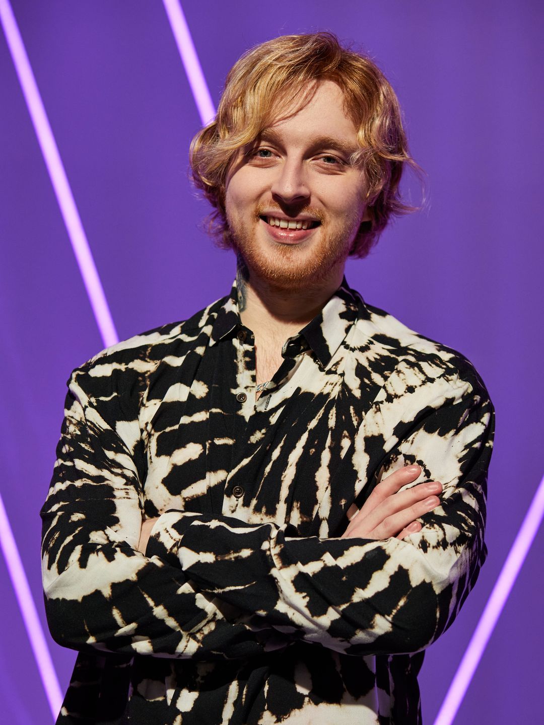 Craig Eddie with his arms crossed standing in a patterned shirt