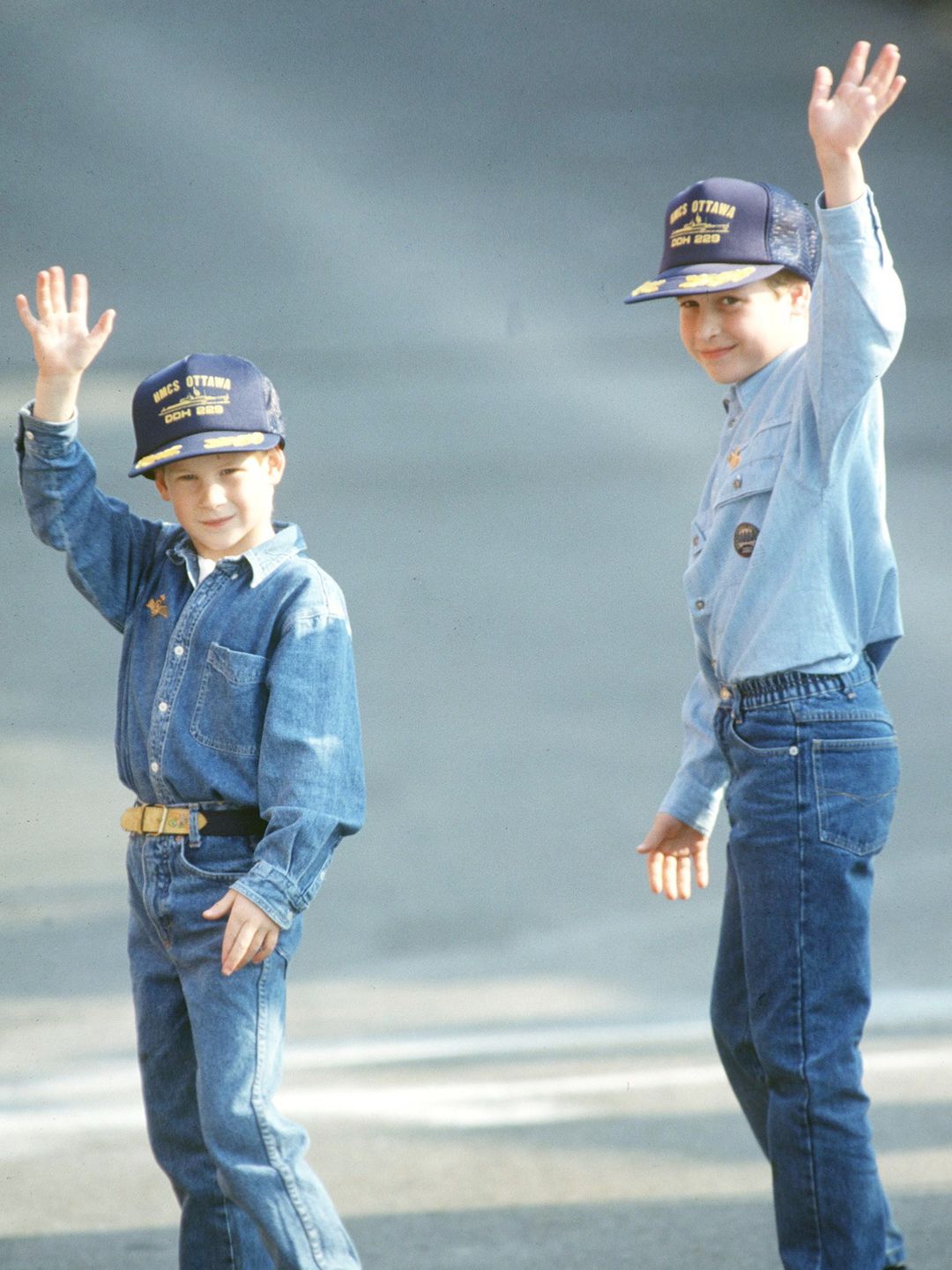A young Prince William and Prince Harry in denim outfits and baseball caps