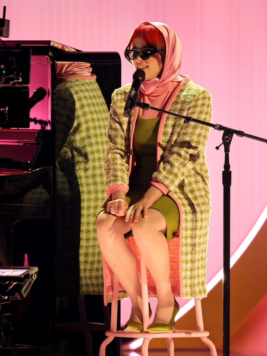 Billie Eilish performs onstage during the 66th GRAMMY Awards wearing a green dress, pink head scarf and green coat