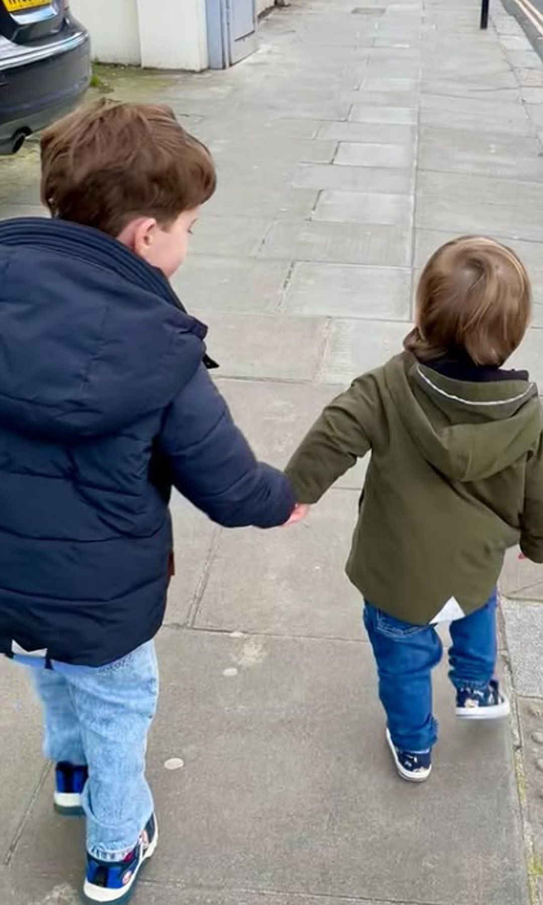 August Brooksbank holding Ernest Brooksbank's hand as they walk down a street