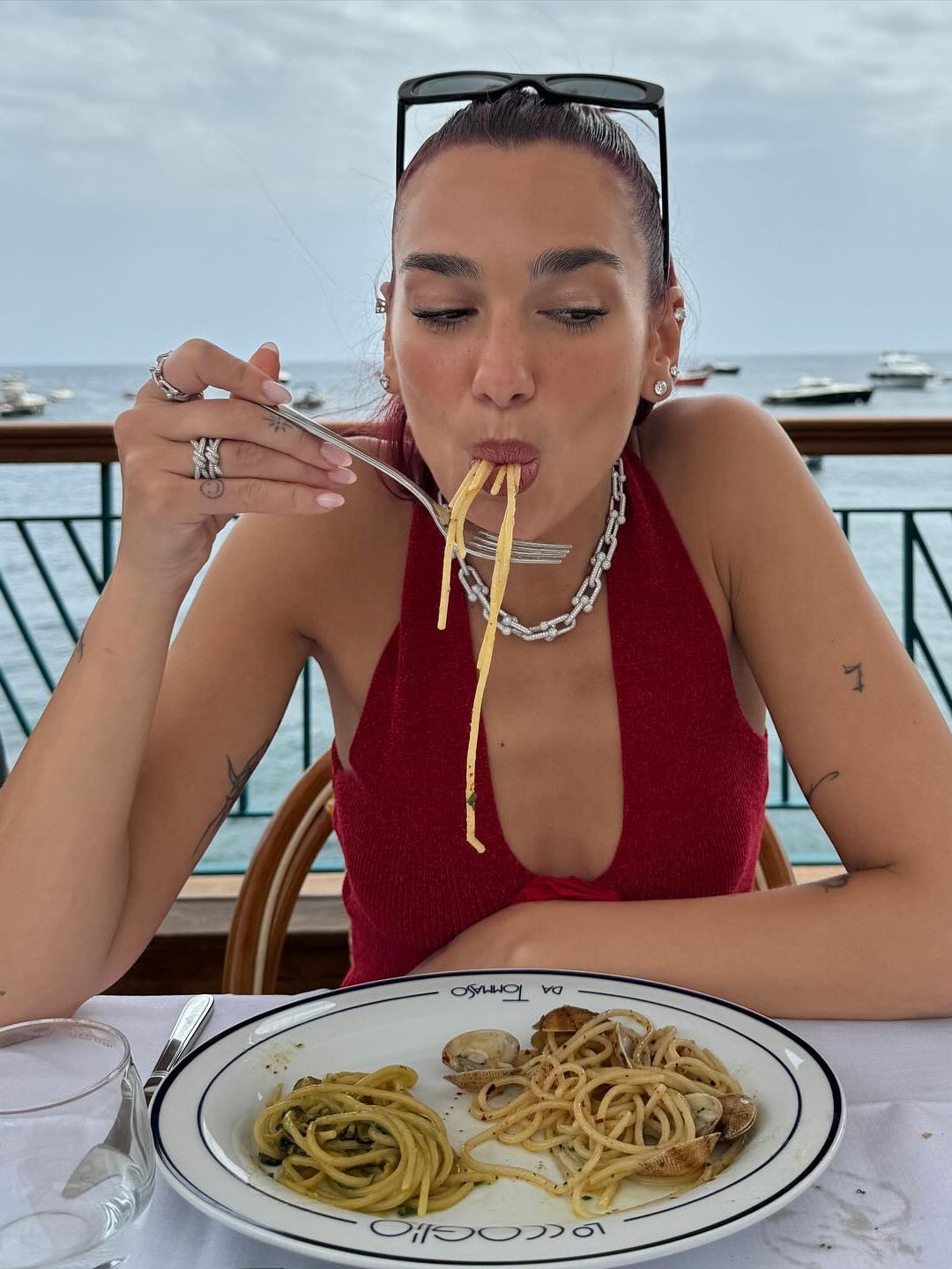 Dua Lipa eats pasta in Italy in a red top and diamond jewellery