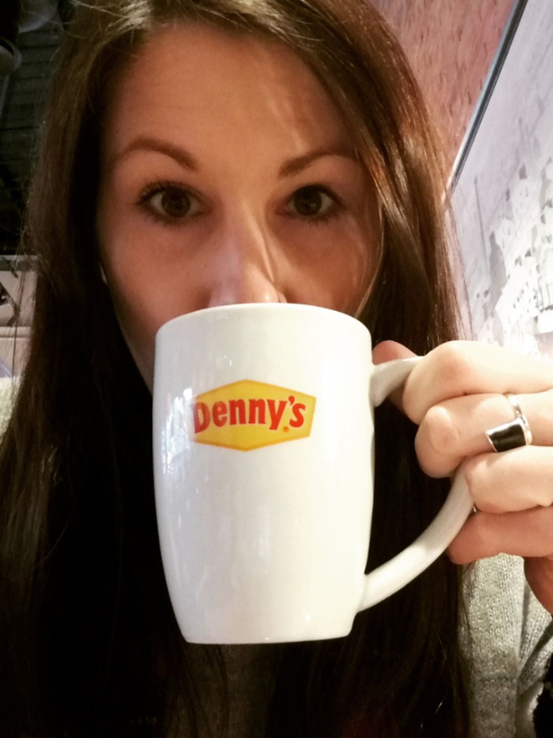 Catherine Gee drinking from a Denny's mug