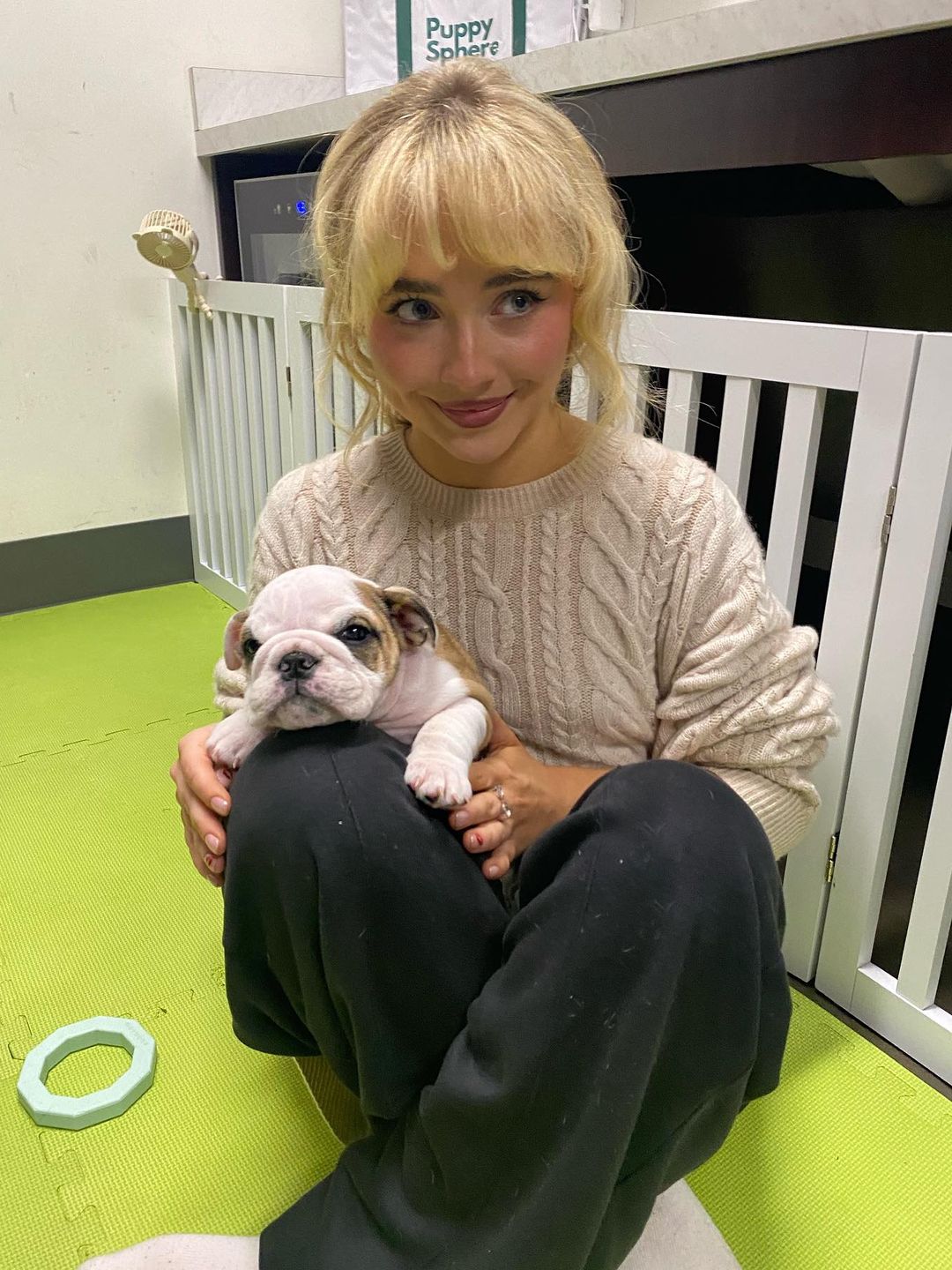 Sabrina Carpenter cuddles a puppy in her sweat pants and a beige cable knit