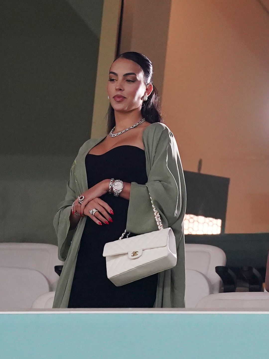 Cristiano Ronaldo's girlfriend Georgina Rodriguez in the stands before the FIFA World Cup Round of Sixteen match at the Lusail Stadium in Lusail, Qatar wearing a black dress, green coat and white chanel bag