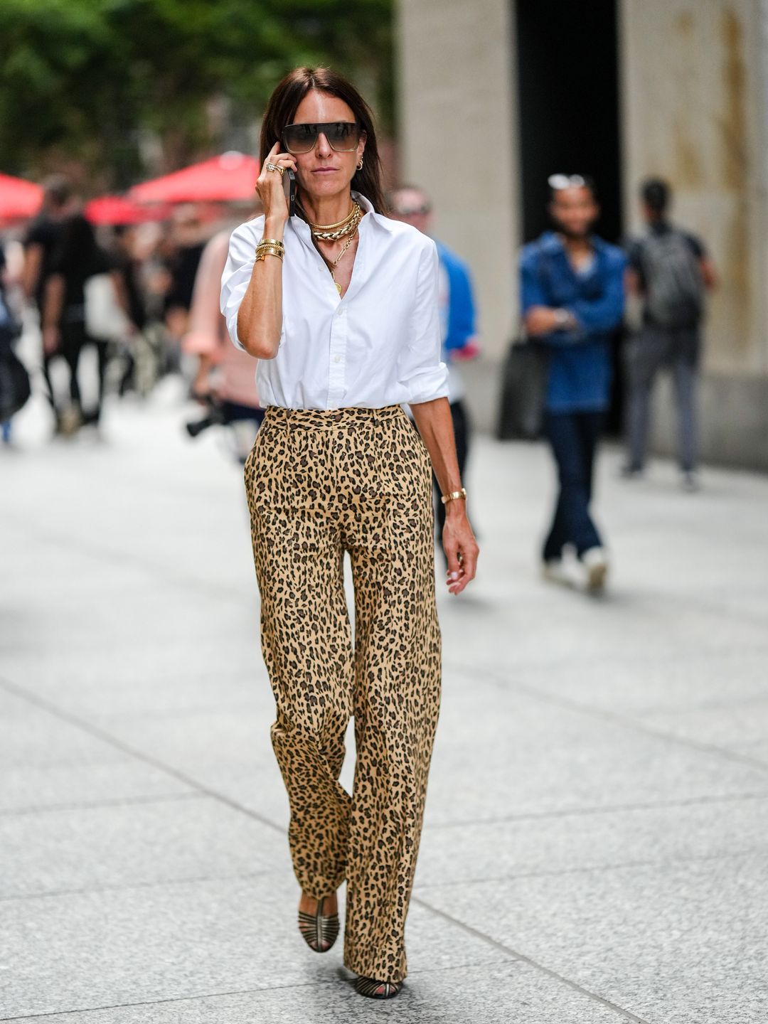 A fashion week guest teams a white shirt with leopard print trousers 