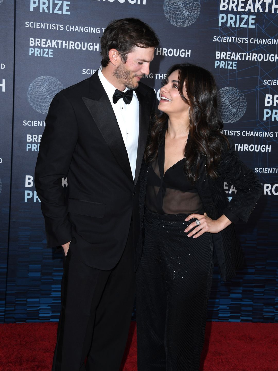Ashton Kutcher and Mila Kunis smiling at each other on a red carpet