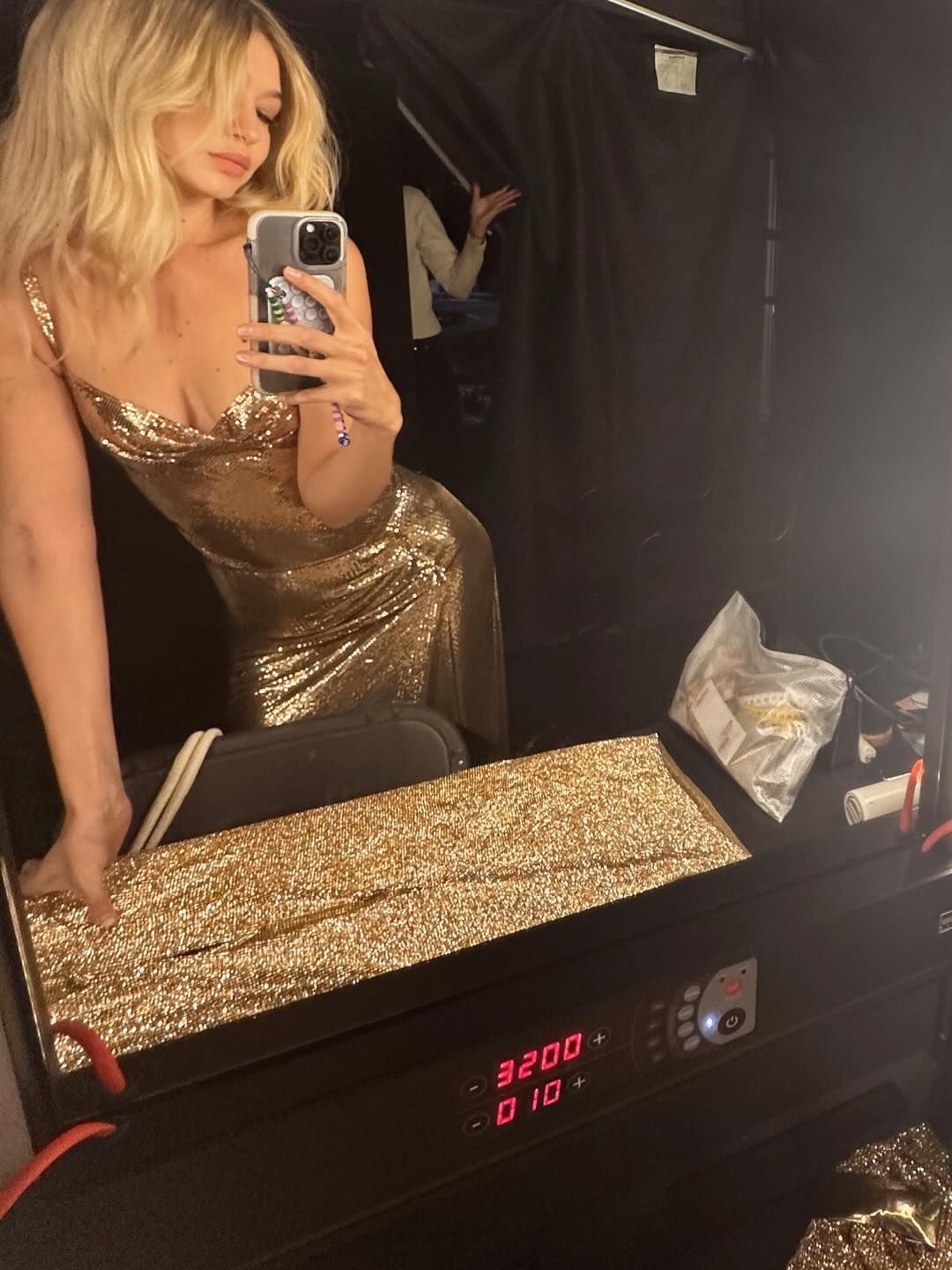 Gigi Hadid takes a mirror selfie on set in a gold gown