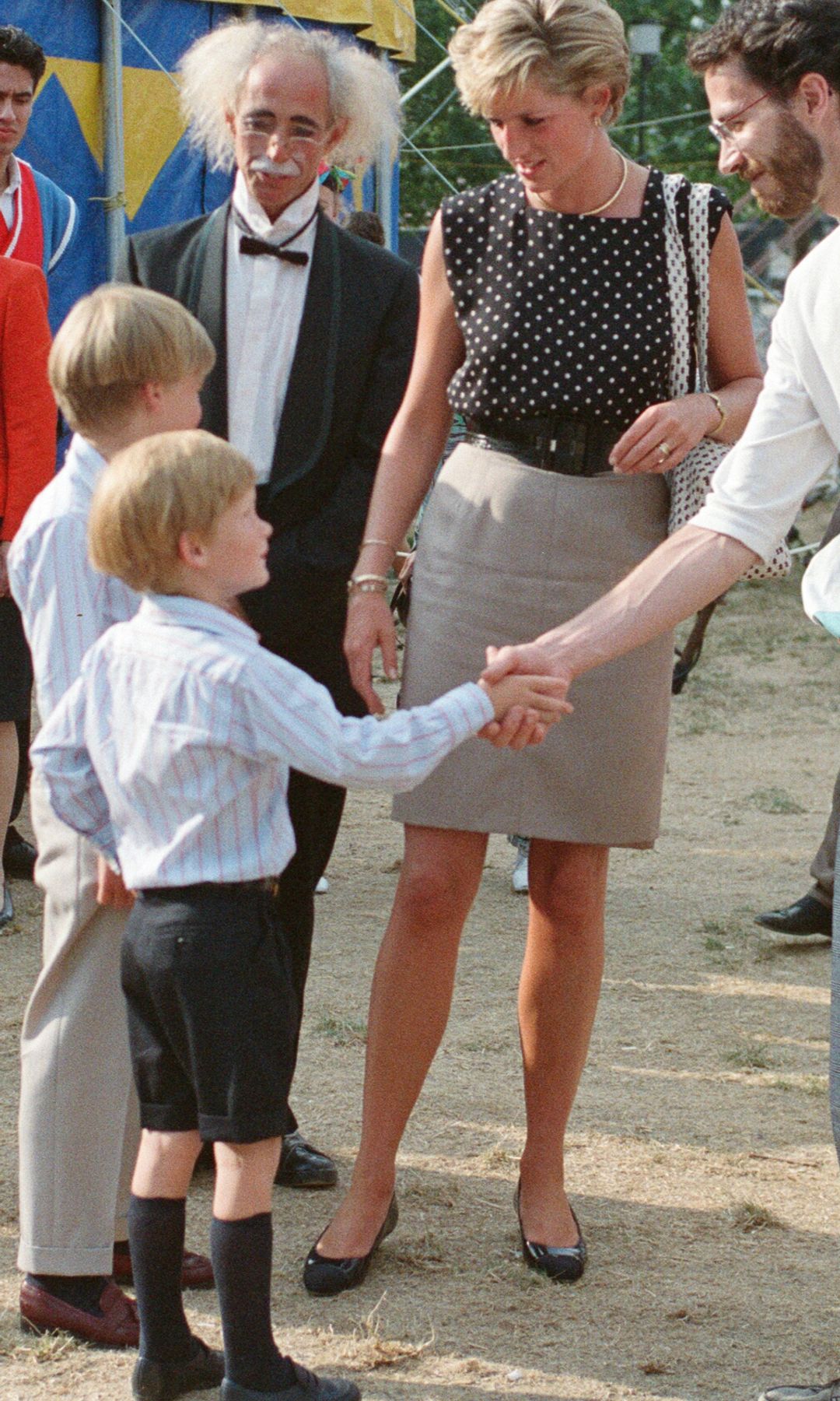Prince Harry shaking hands in black shorts and a shirt