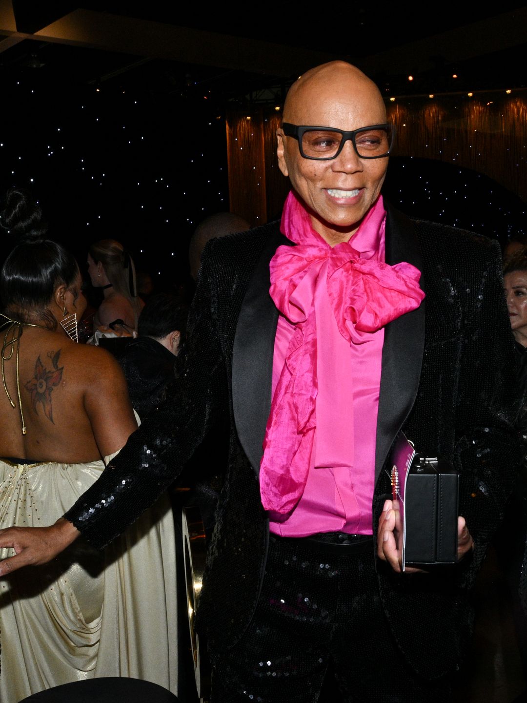 RuPaul sports a hot pink blouse and black sequin suit at the 75th Emmy Gala