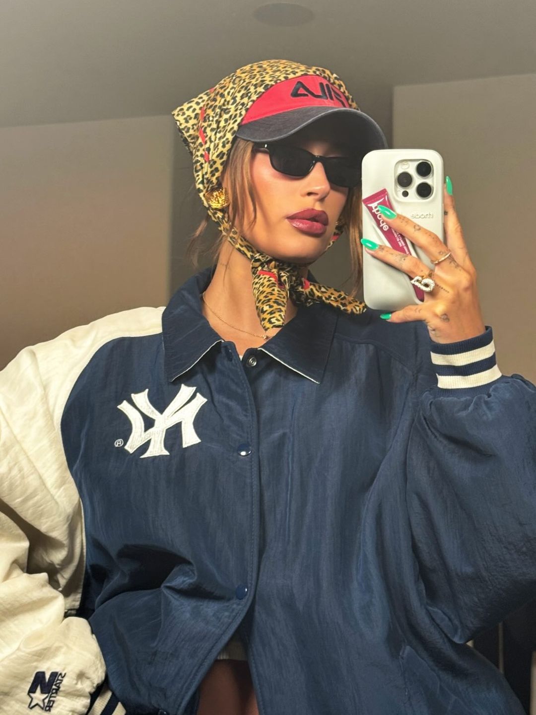 Hailey Bieber poses in a blue jacket, sunglasses, a cap and headscarf 