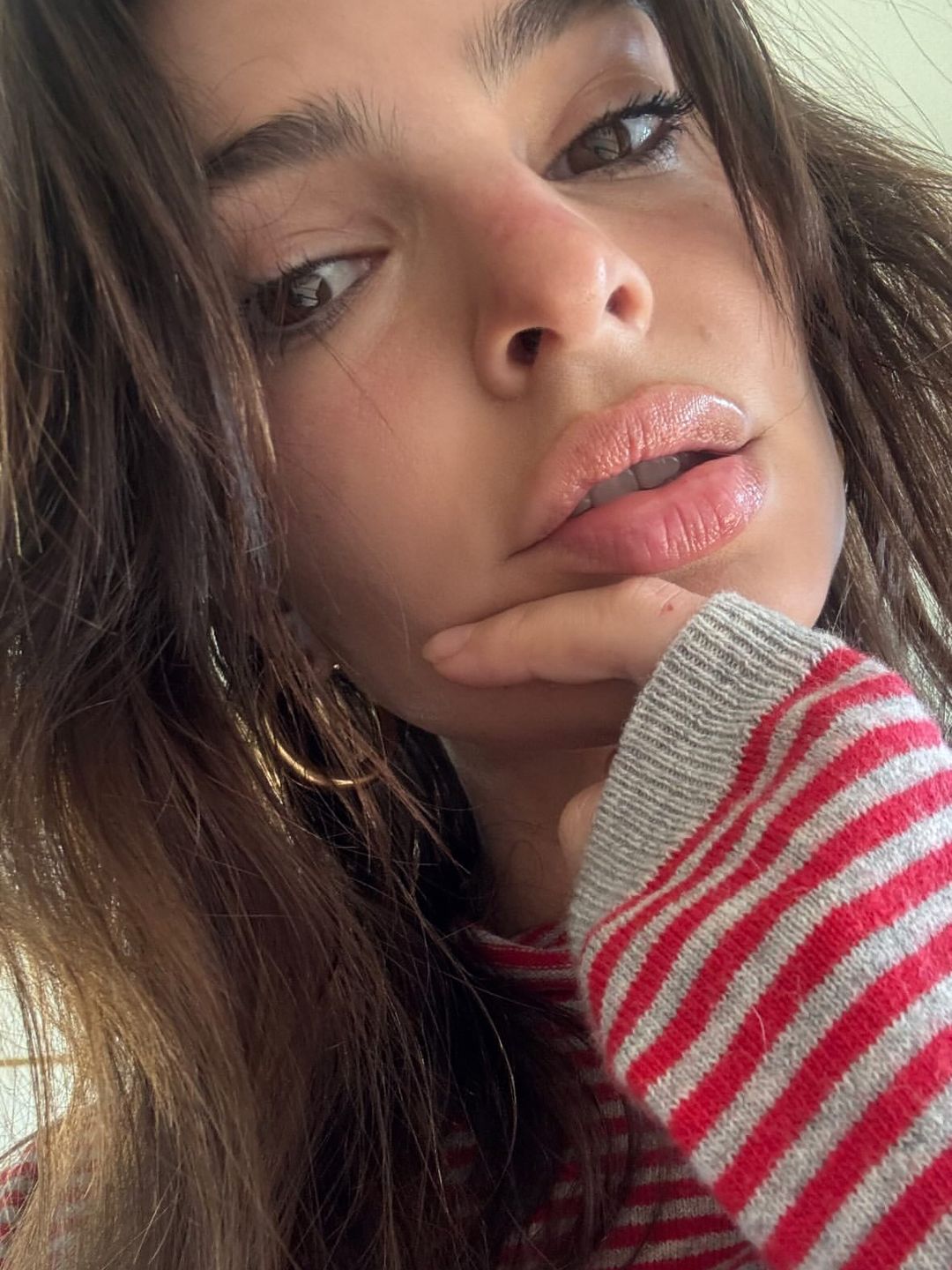 Emily Ratajkowski poses for a selfie in a red and grey striped knit