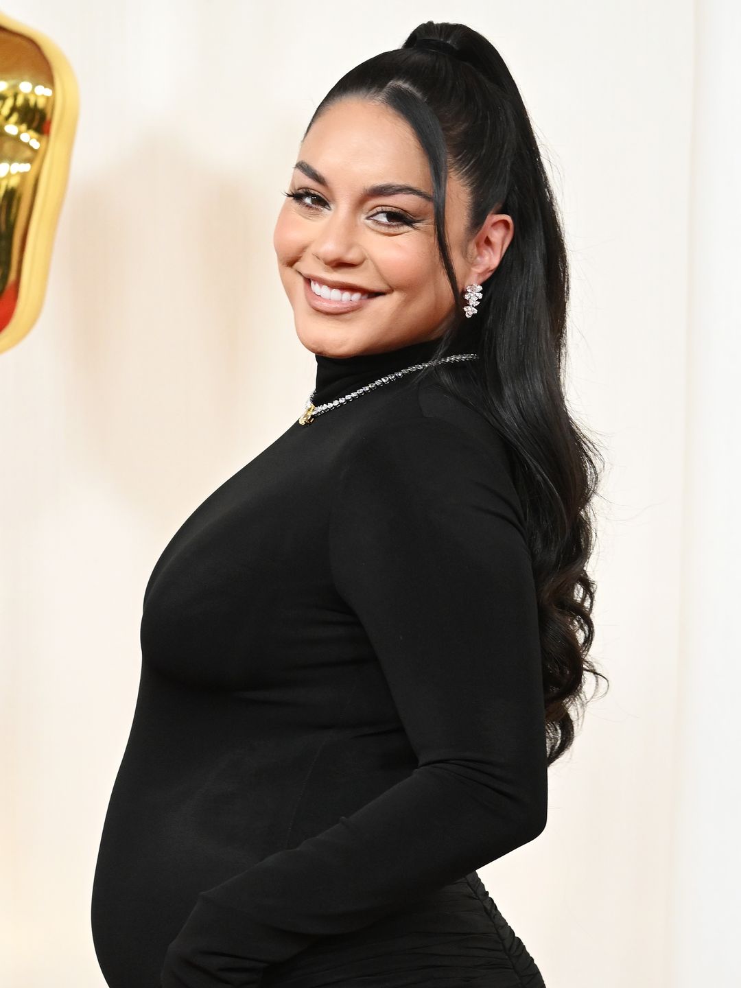 Vanessa Hudgens smiling wearing a black high-necked dress at the Oscars 