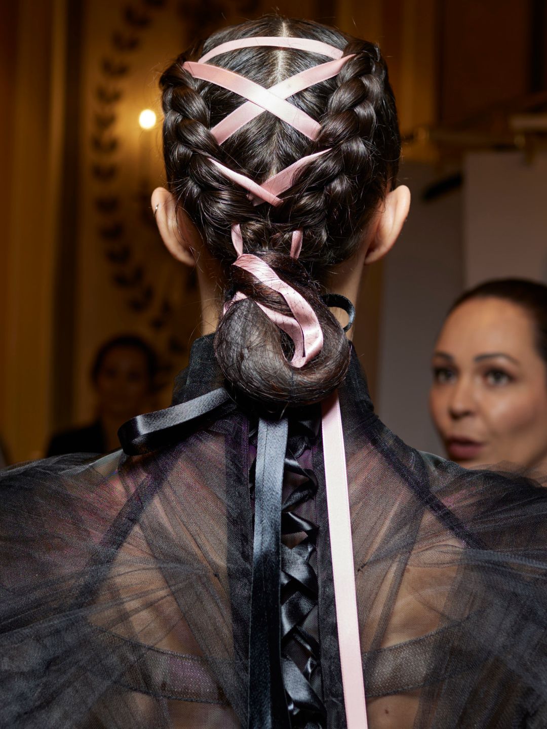 Model with braided bun, woven with criss-cross pink bows at Christian Siriano SS24 