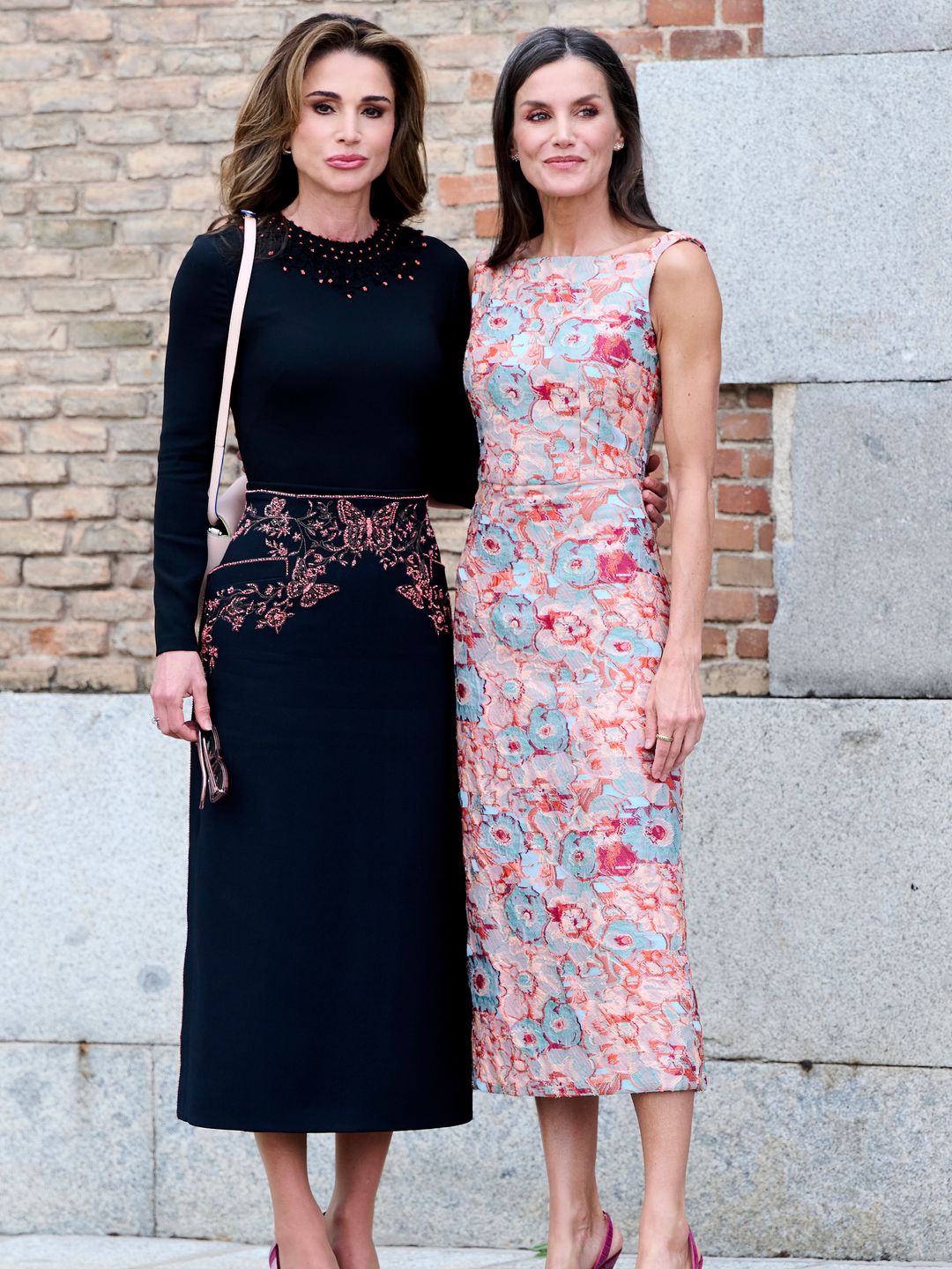 Queen Rania poses in black dress with a hint of pink, complementing Queen Letizia's pink dress