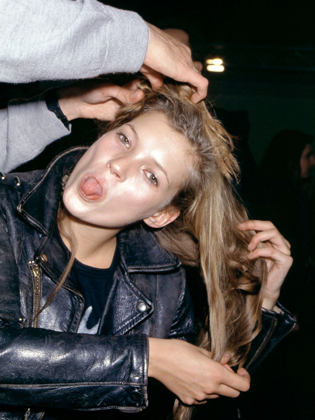 Kate Moss wears a leather jacket whilst goofing around back stage at Vivienne Westwood's A/W 1994 show