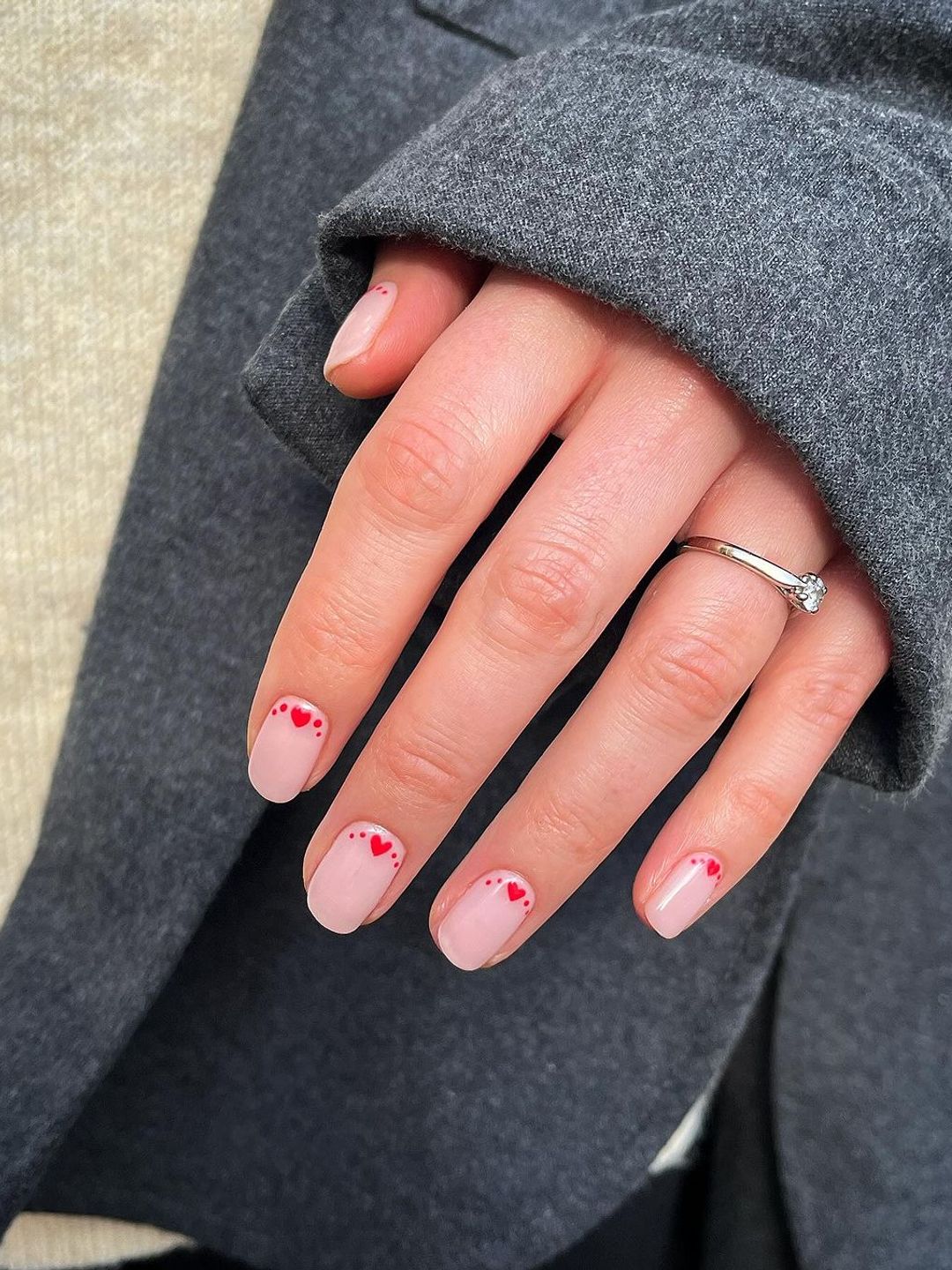 Pink nails with red line of hearts near the cuticle 