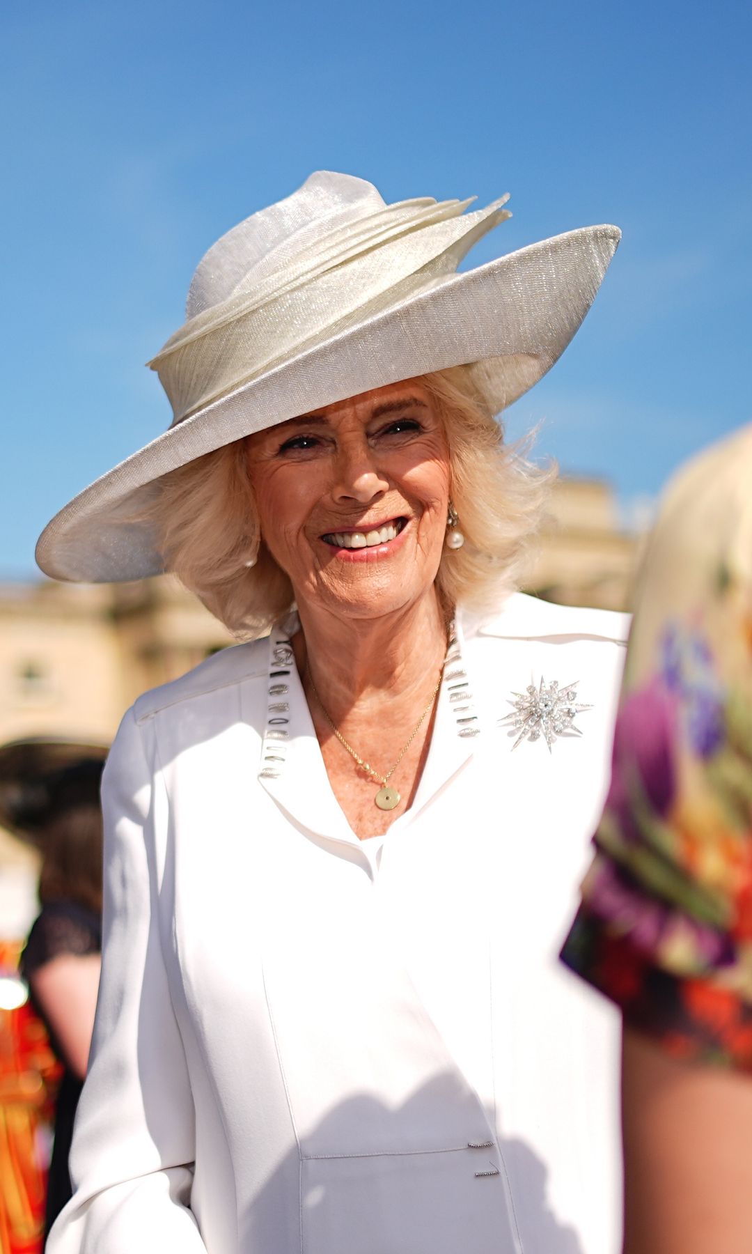 Queen Camilla smiling in a white outfit